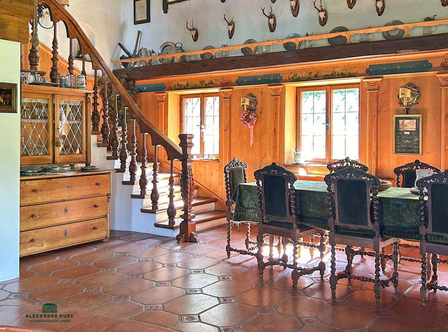 Traditioneller Essbereich mit holzgetäfelten Wänden, Hirschgeweihen und Terrakottafliesen.