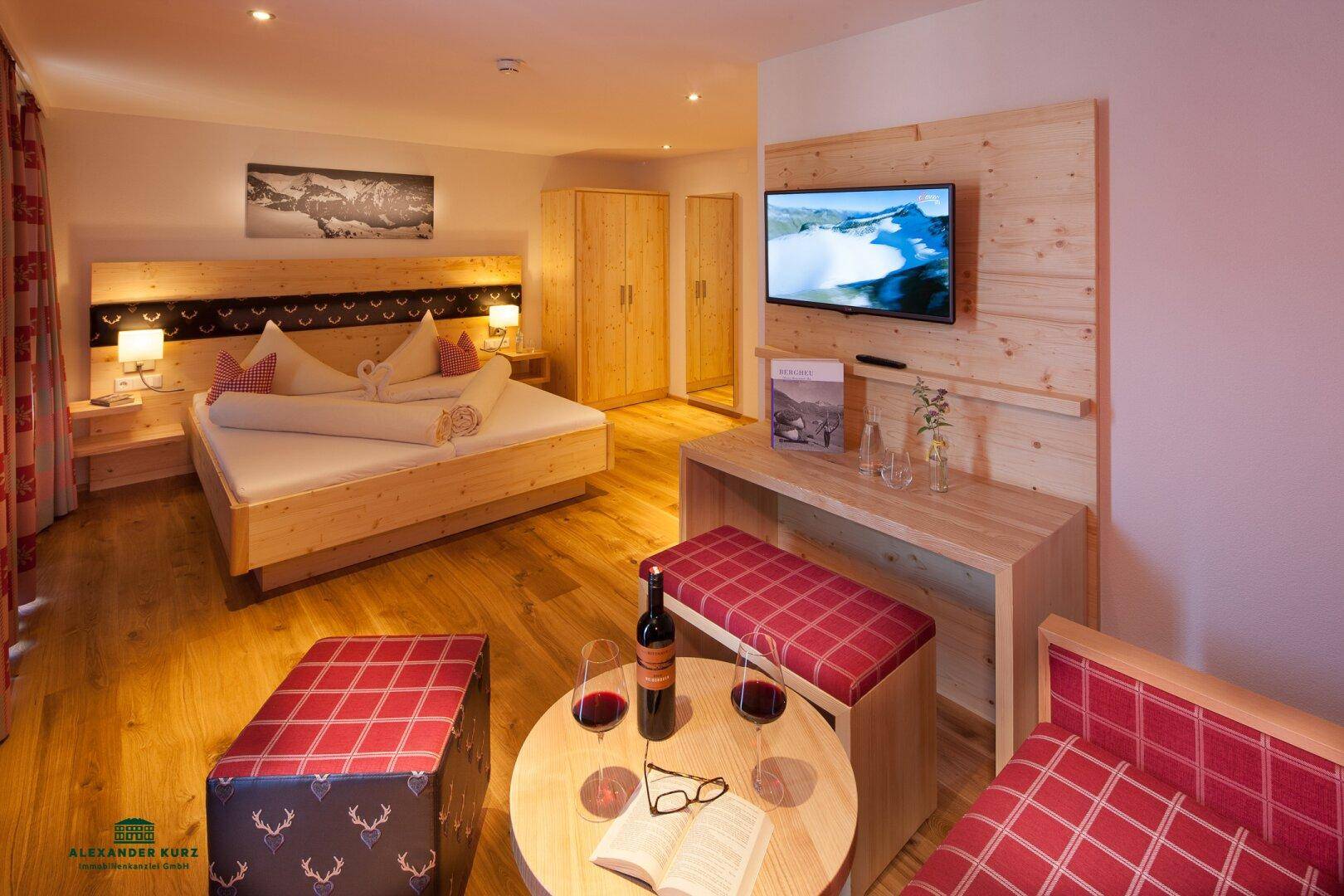 Helles Schlafzimmer mit Holzbett, passenden Möbeln und einem Flachbildfernseher an der Wand.