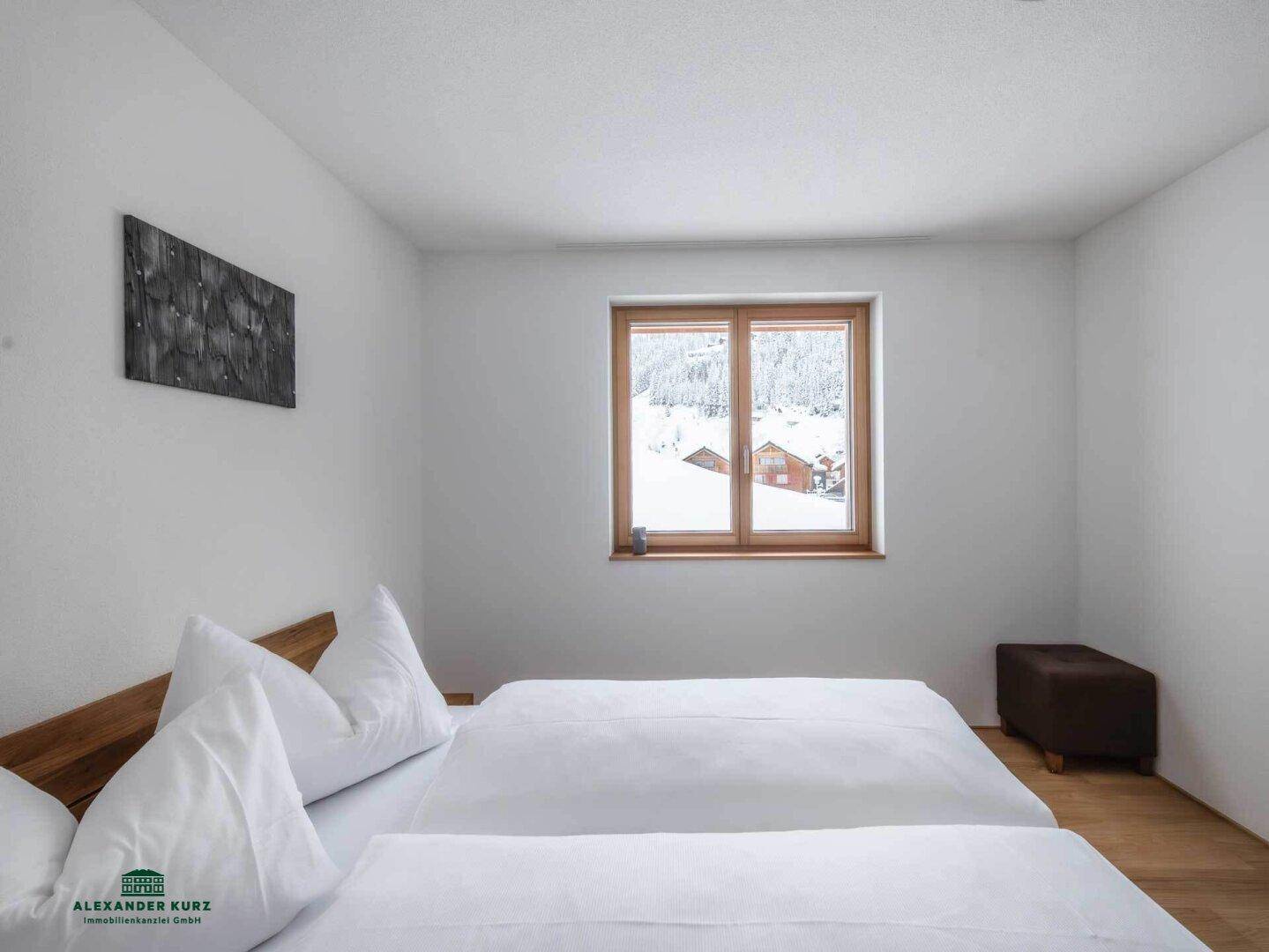 Gemütliches Schlafzimmer mit Doppelbett, Holzboden und Blick auf eine verschneite Landschaft.