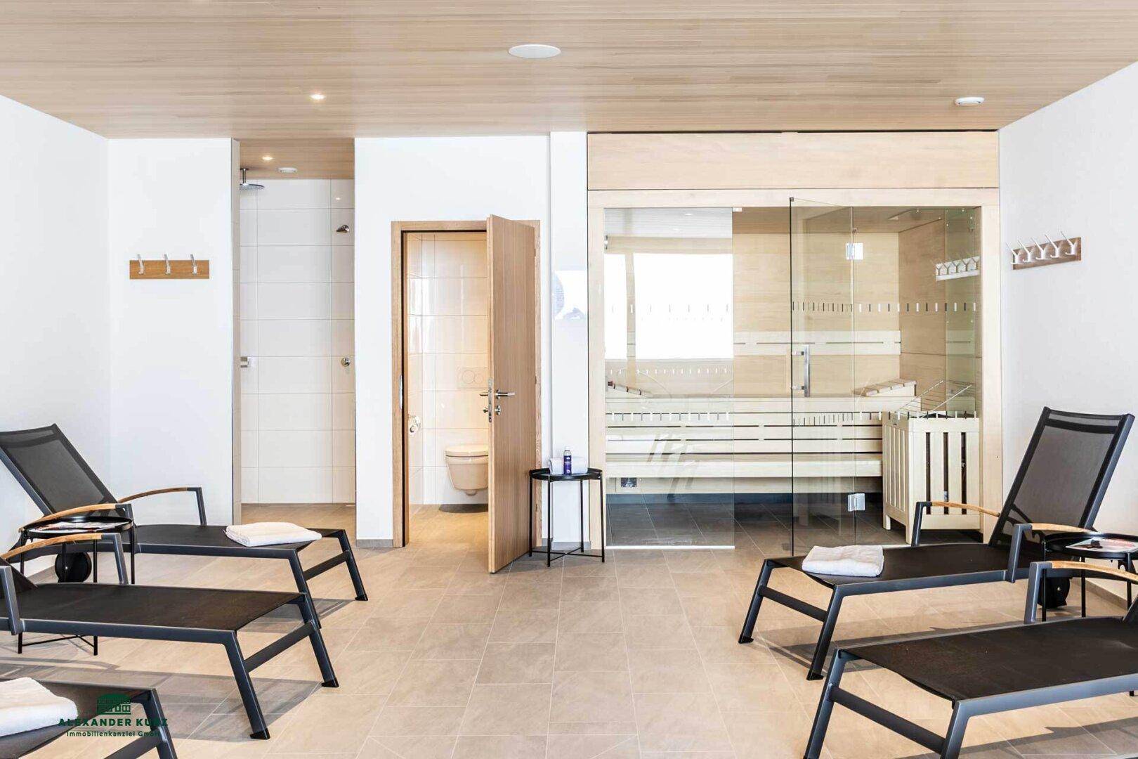 Entspannender Wellnessbereich mit Sauna, Liegestühlen und separaten Duschmöglichkeiten.