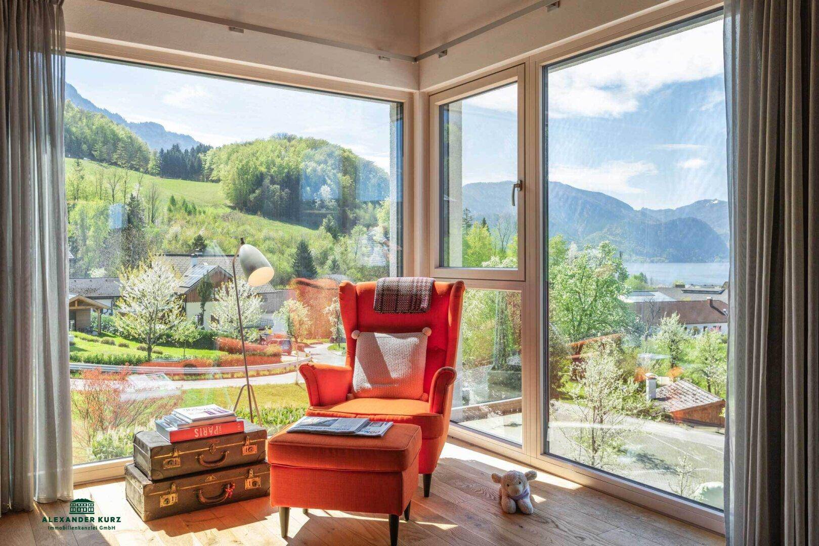 Gemütliche Leseecke mit großen Fenstern, die einen weiten Blick auf See und Berge bieten.