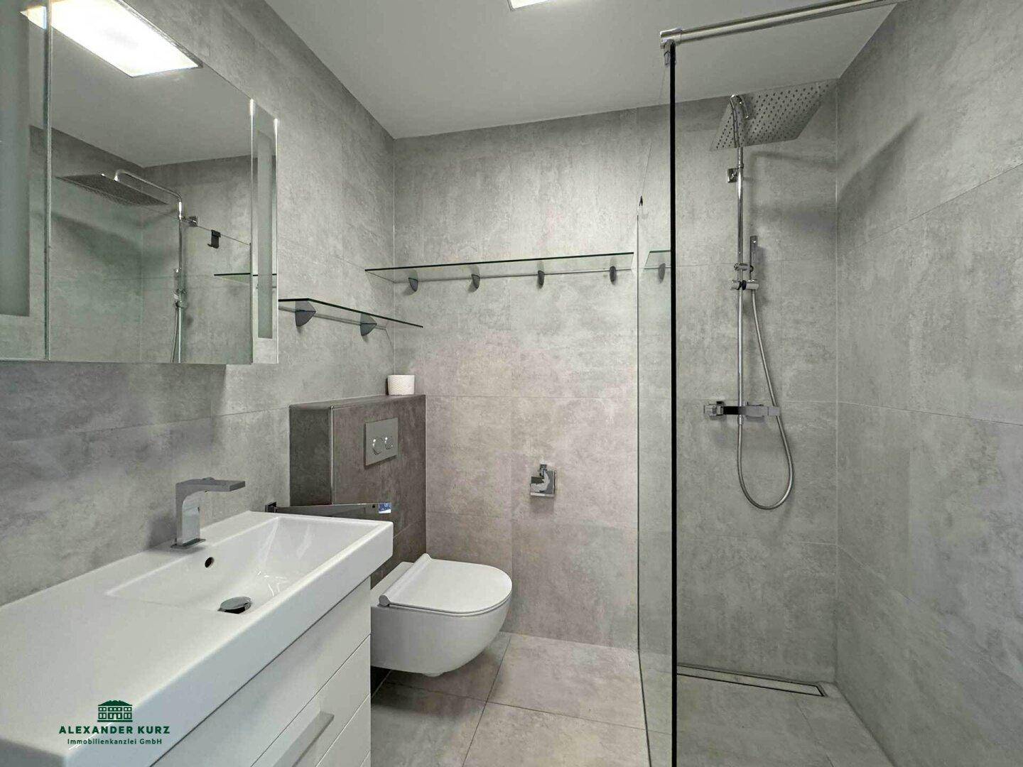 Modernes Badezimmer mit grauen Fliesen, ebenerdiger Dusche und wandhängendem WC.