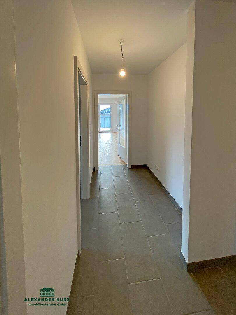 Heller Flur mit modernen Fliesen und Zugang zu den verschiedenen Räumen der Wohnung.