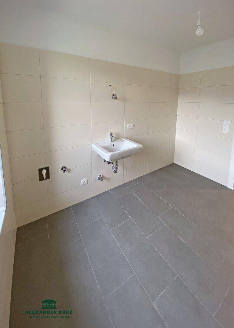 Modernes Badezimmer mit hellen Fliesen, einem Waschbecken und vorbereiteten Anschlüssen.