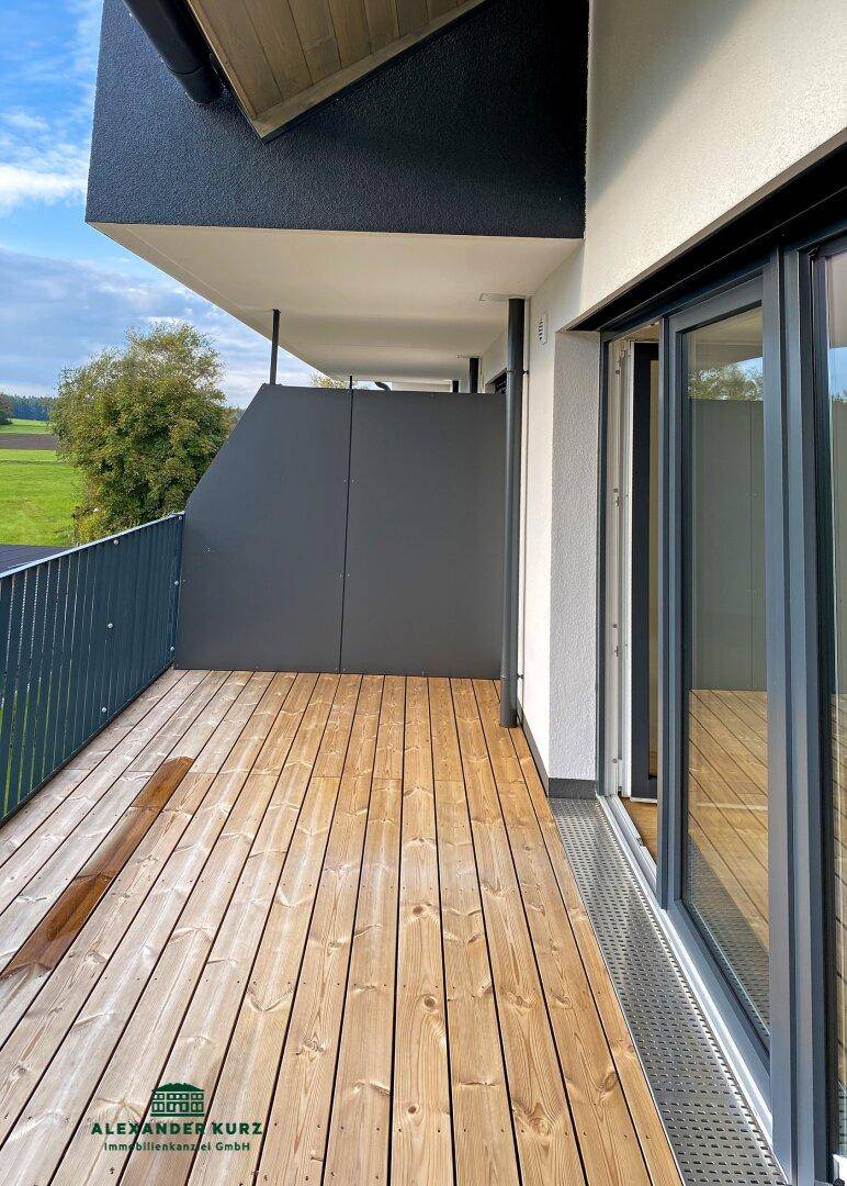 Geräumiger Balkon mit Holzboden und weitem Blick über die umliegende Landschaft.