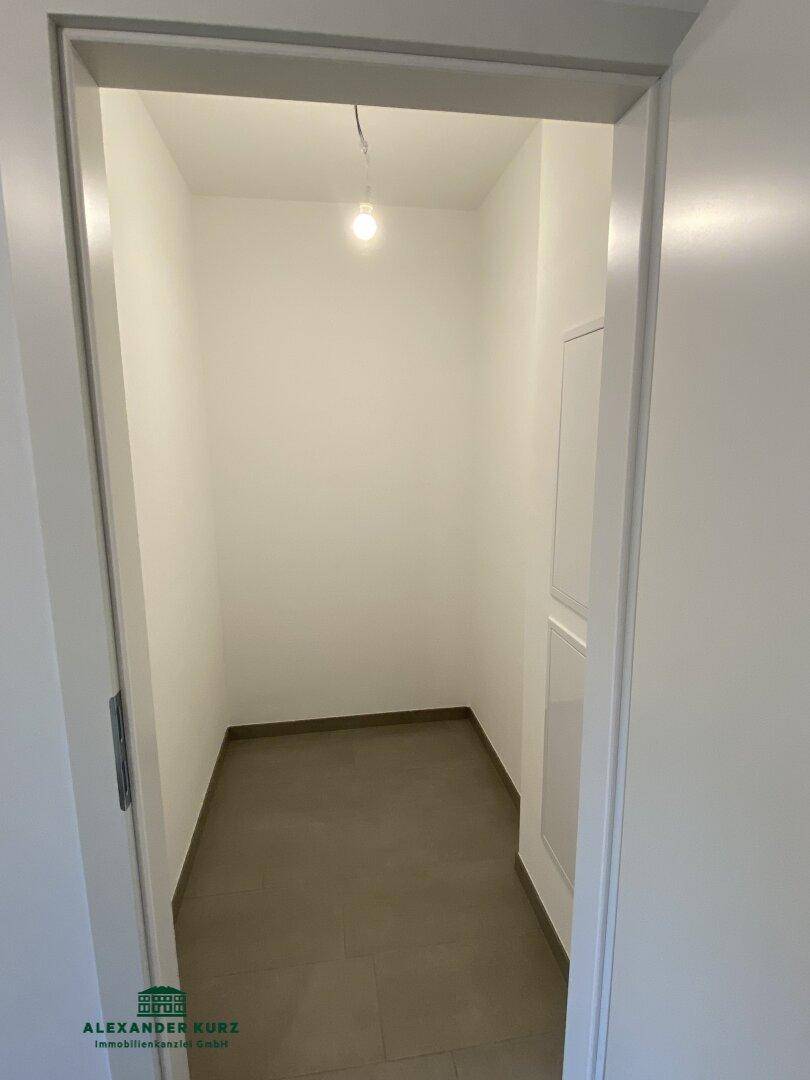 Praktischer Abstellraum mit Fliesenboden und weißen Wänden für zusätzlichen Stauraum.