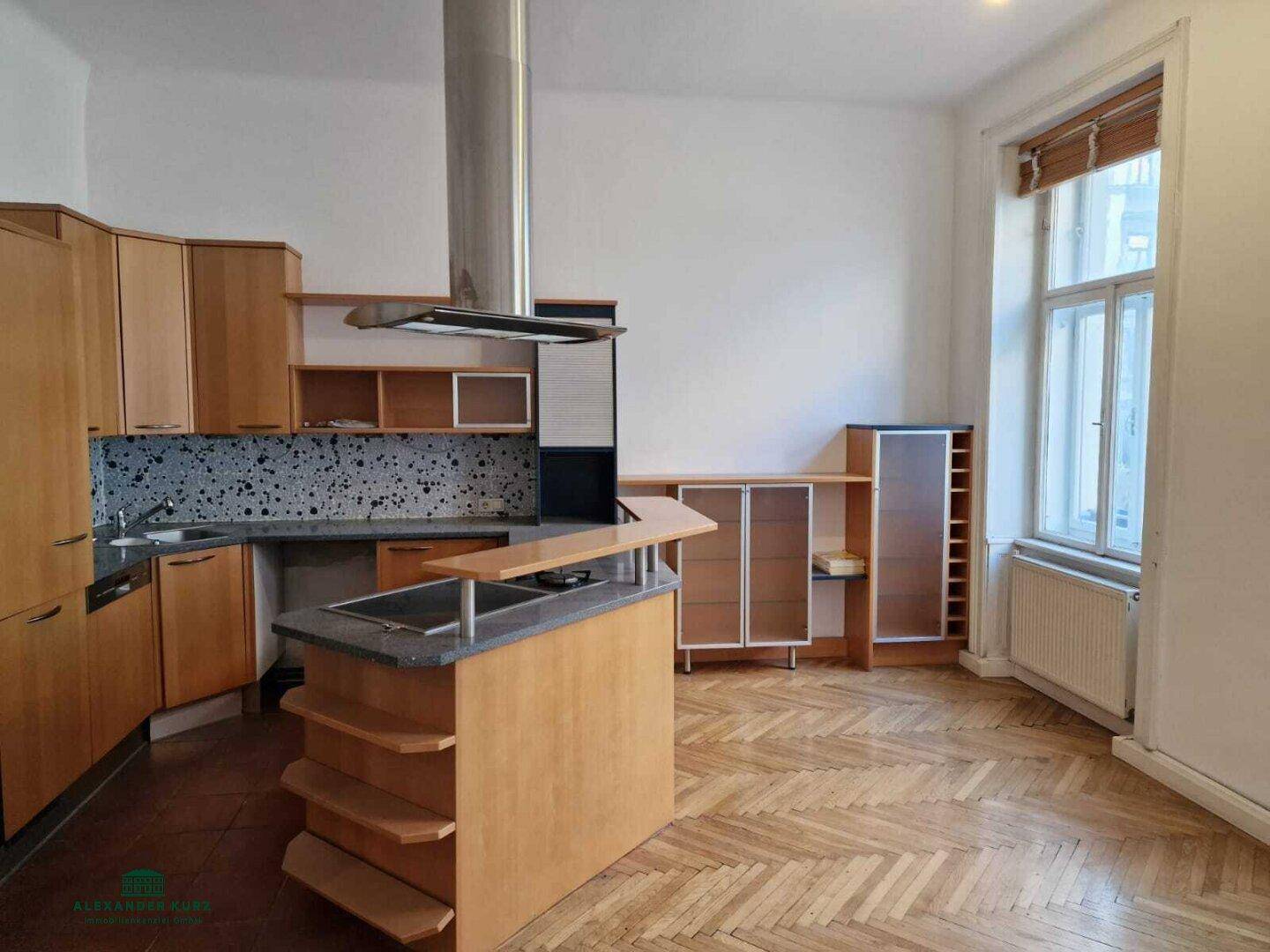 Geräumige Küche mit Holzschränken, Kochinsel und Dunstabzugshaube, bereit zur Modernisierung.