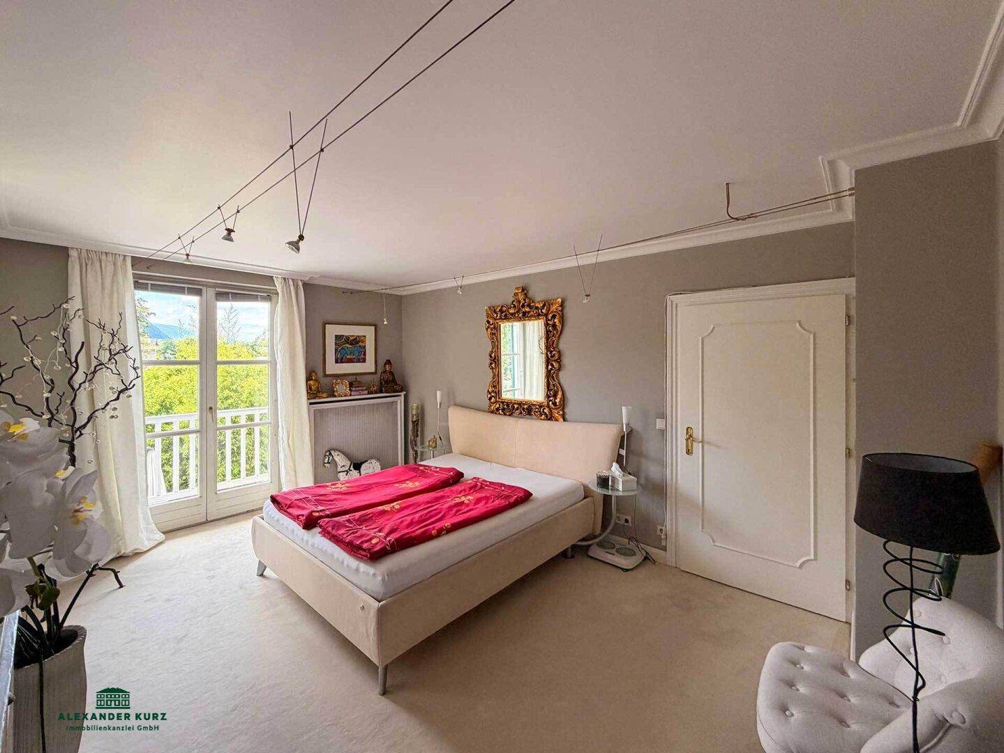 Ruhiges Schlafzimmer mit Doppelbett, elegantem Spiegel und Zugang zu einem französischen Balkon mit Ausblick.