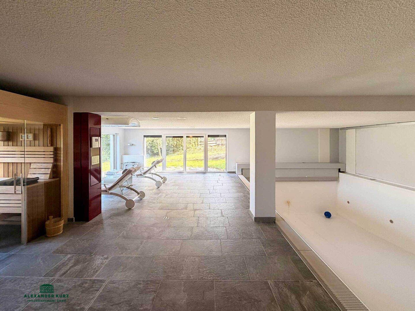 Großzügiger Wellnessbereich mit Innenpool, Sauna und Liegestühlen, mit Zugang zum Garten.