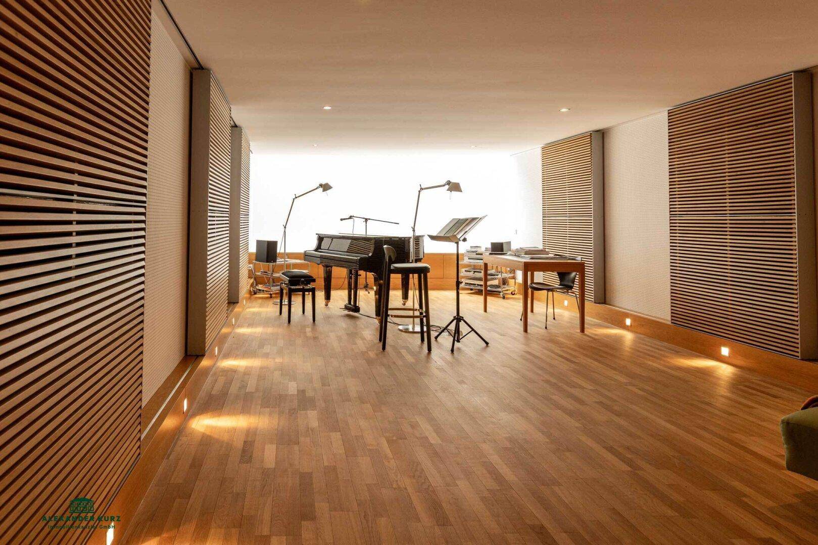 Geräumiger Musikraum mit Flügel, Holzparkett und akustischen Wandpaneelen.