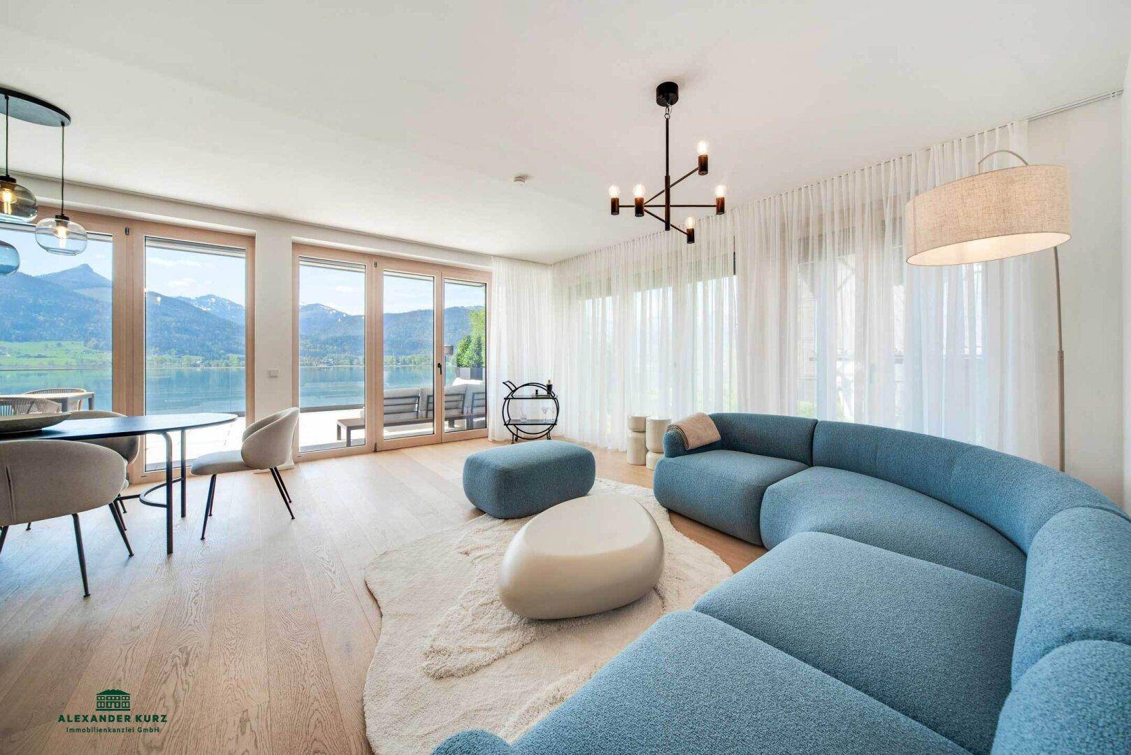 Heller offener Wohn-Essbereich mit modernem Sofa und großen Fenstern mit See- und Bergblick auf Hartholzboden.