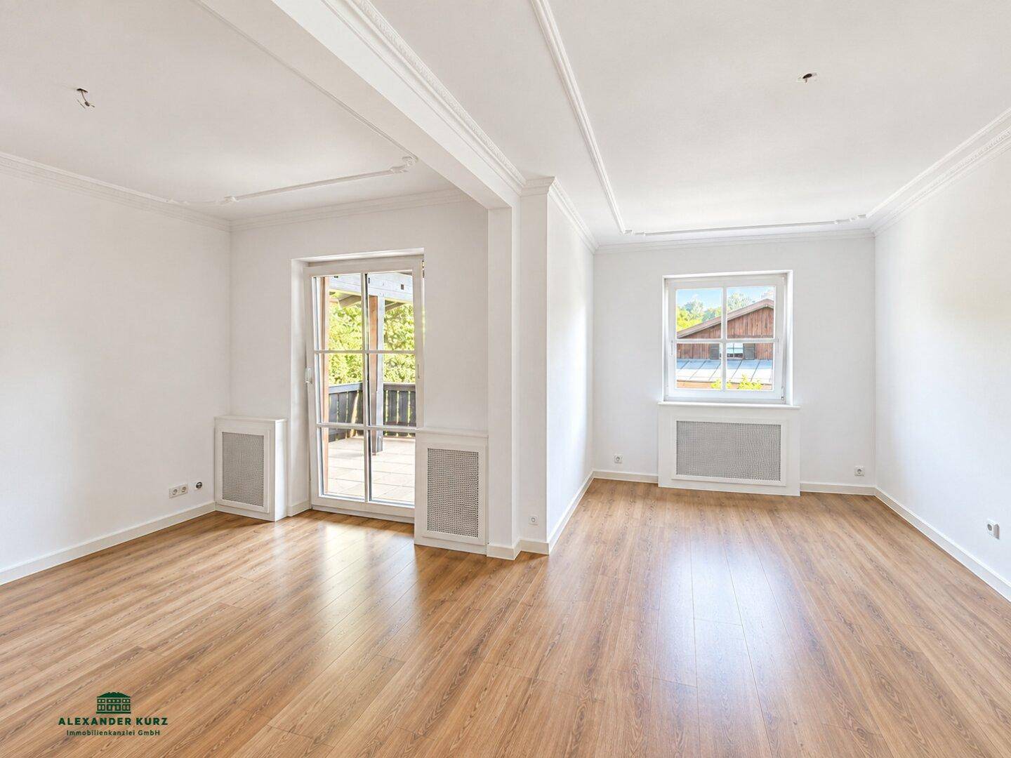 Heller Wohnbereich mit Laminatboden, dekorativen Deckenleisten und Zugang zur Terrasse.