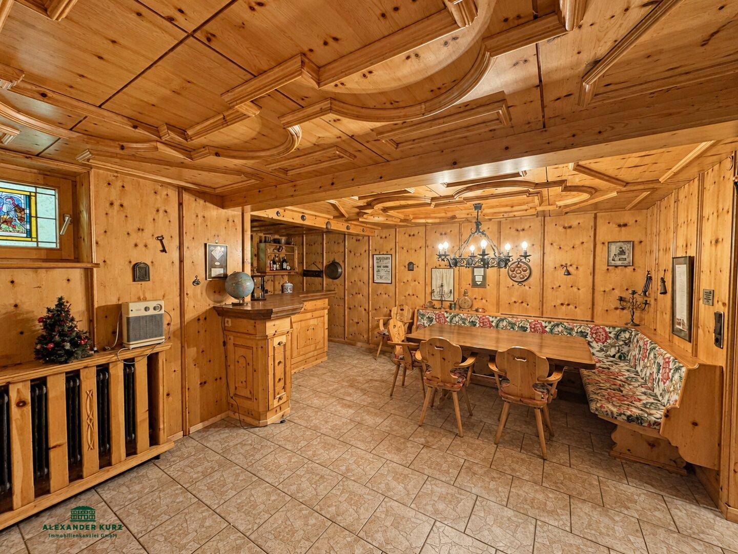 Rustikaler Wohn- und Essbereich im alpinen Stil mit Holztäfelung, Bar und traditionellen Möbeln.