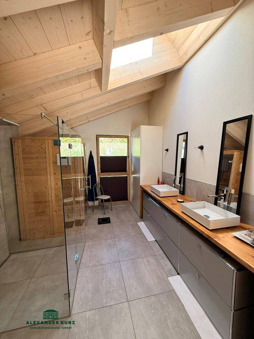 Modernes Badezimmer mit Doppelwaschbecken, begehbarer Dusche und Dachfenster für viel Licht.