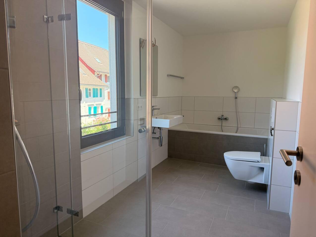 Modernes Badezimmer mit Badewanne, Duschbereich und Fenster für natürliches Licht.