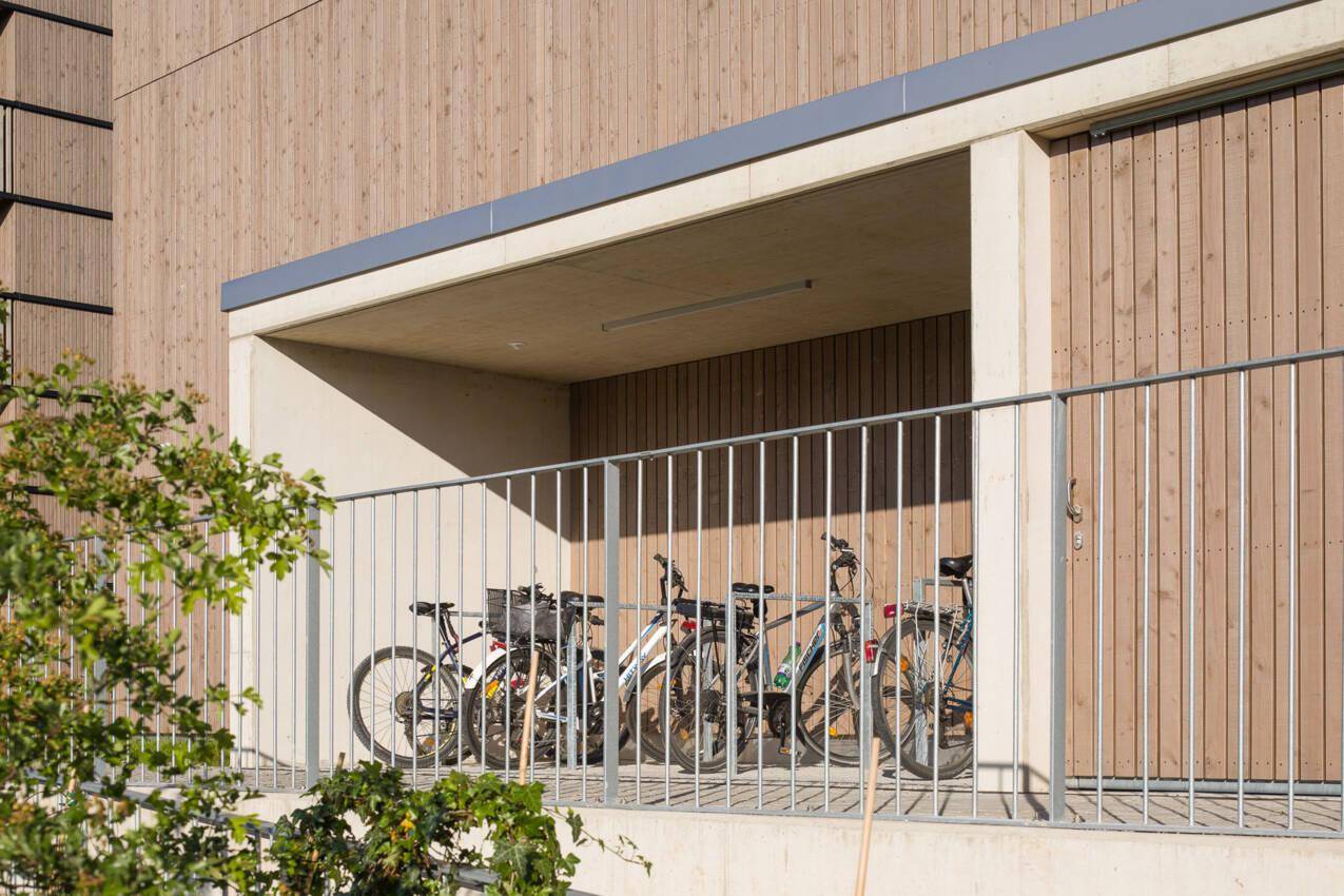 Überdachter Fahrradabstellplatz mit mehreren Fahrrädern an einem modernen Gebäude.
