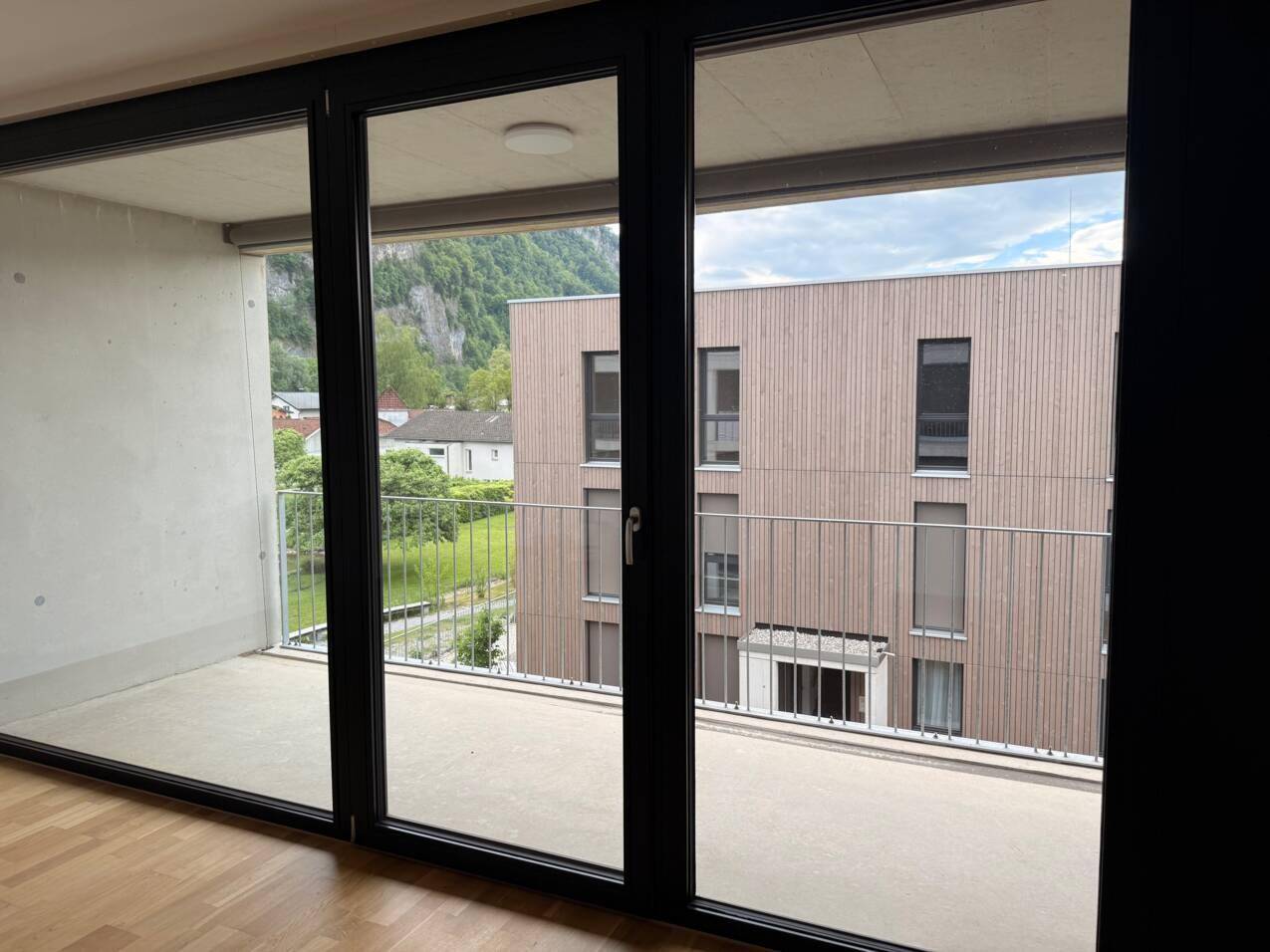 Heller Innenraum mit großen Schiebetüren, die Zugang zu einem Balkon mit Bergblick bieten.