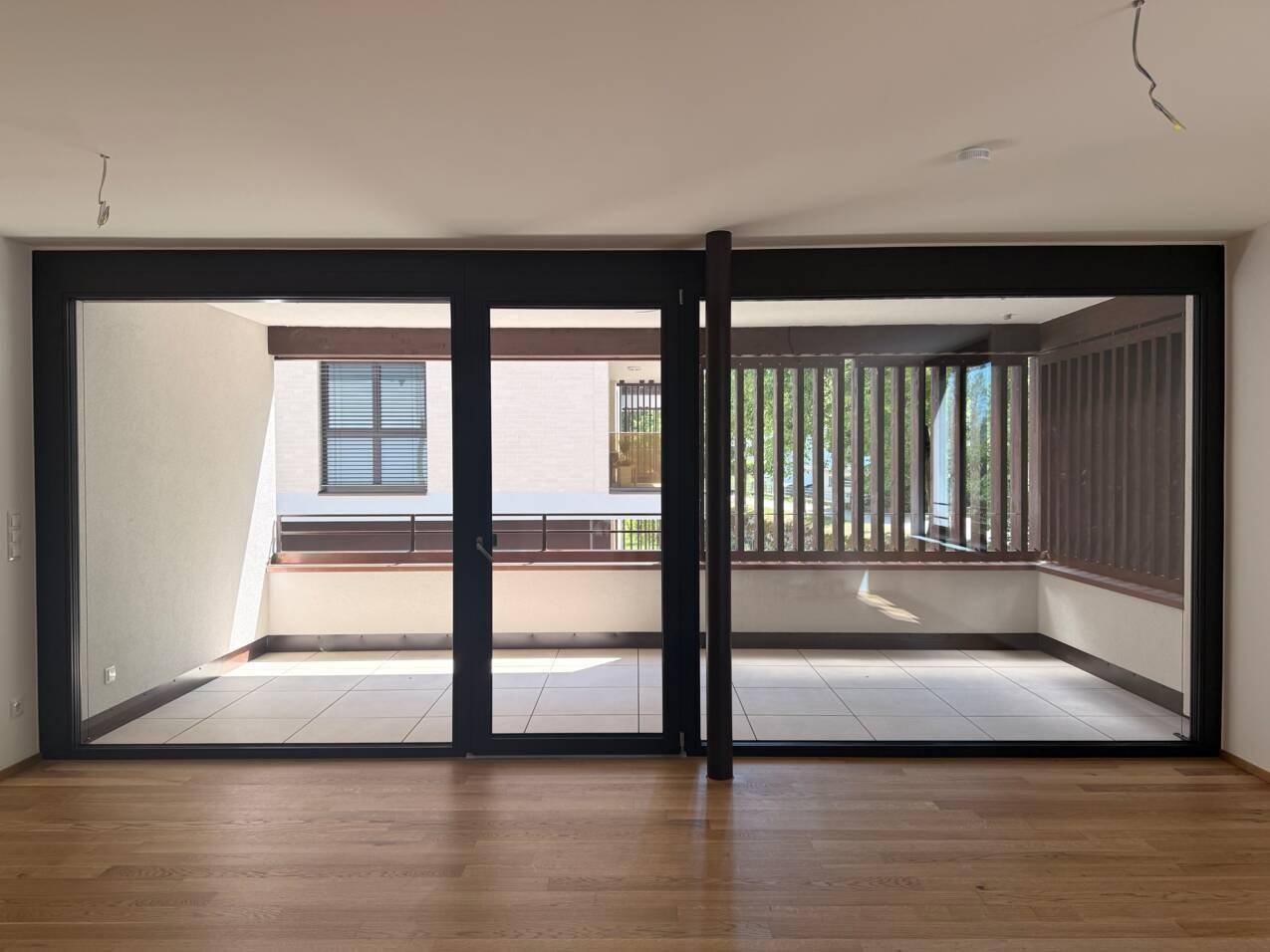 Helles Wohnzimmer mit großen Fensterfronten und direktem Zugang zu einem sonnigen Balkon.