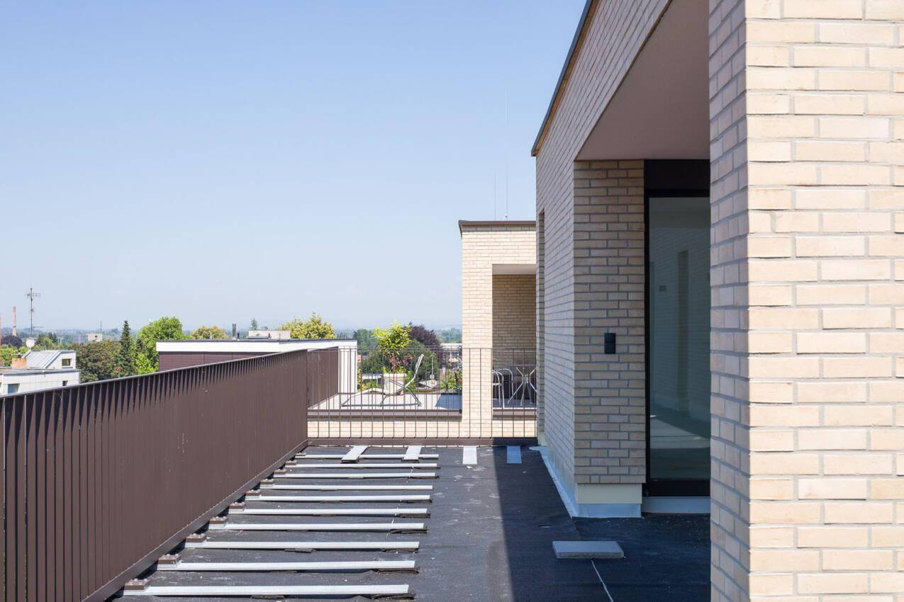 Dachterrasse im Bau mit braunem Geländer und weitem Blick über die Umgebung.