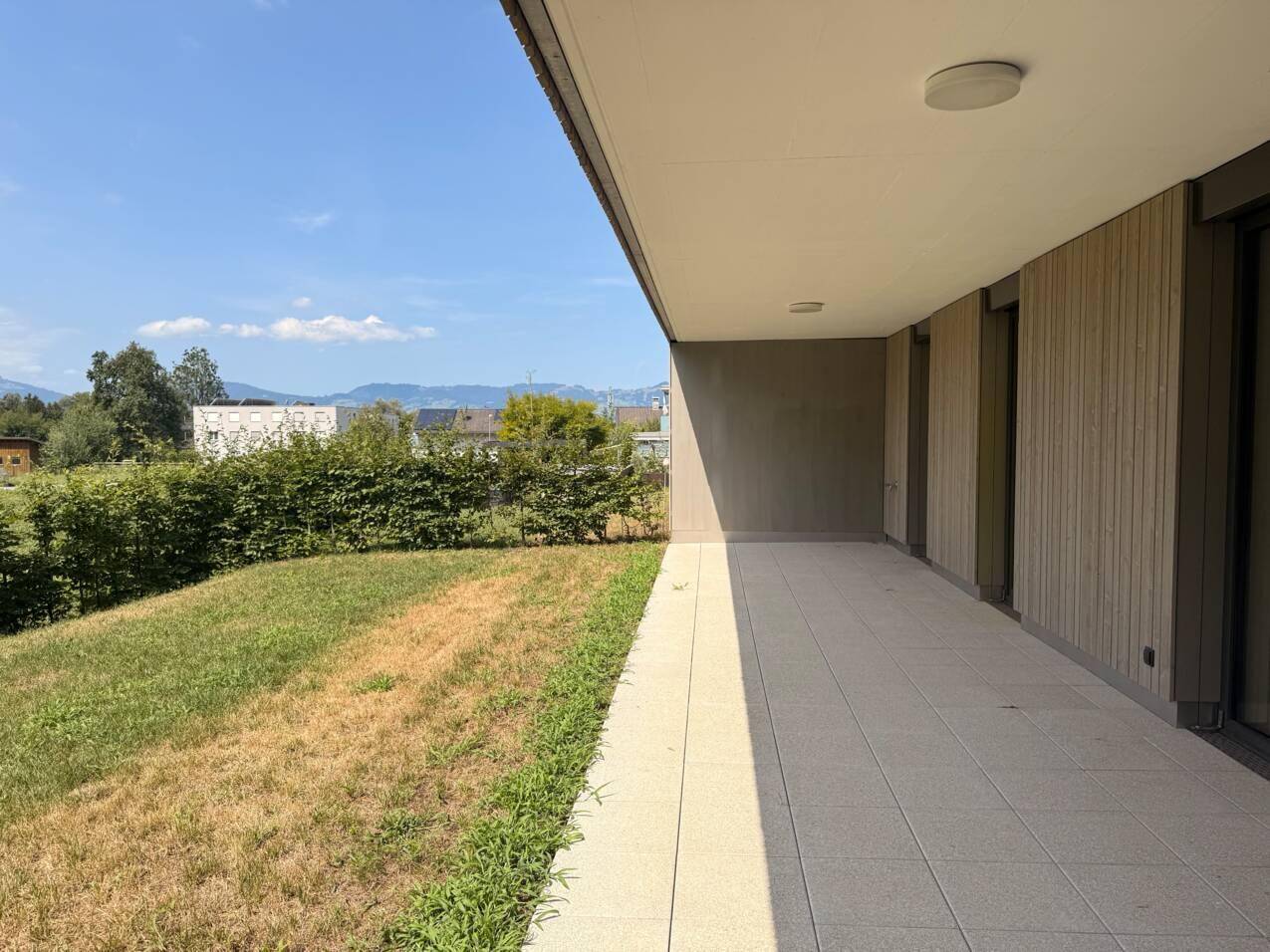 Geräumige, geflieste Terrasse mit moderner Architektur und weitem Blick ins Grüne.