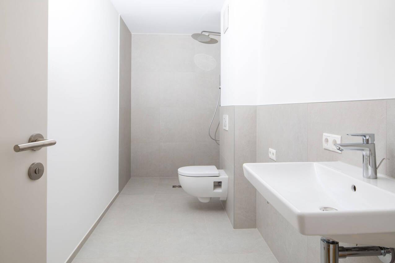 Modernes Badezimmer mit Duschbereich, wandhängendem WC und Einzelwaschbecken.