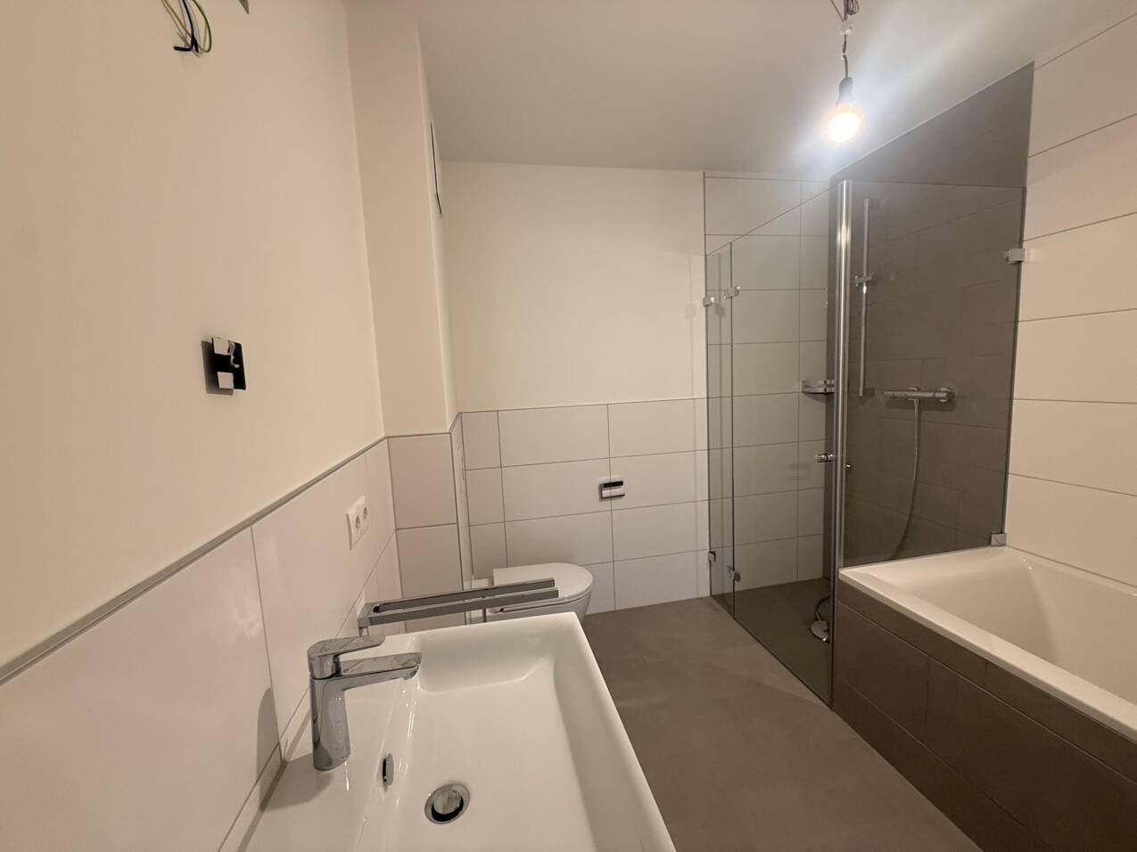 Modernes Badezimmer mit Badewanne, begehbarer Dusche und hellen großformatigen Fliesen.
