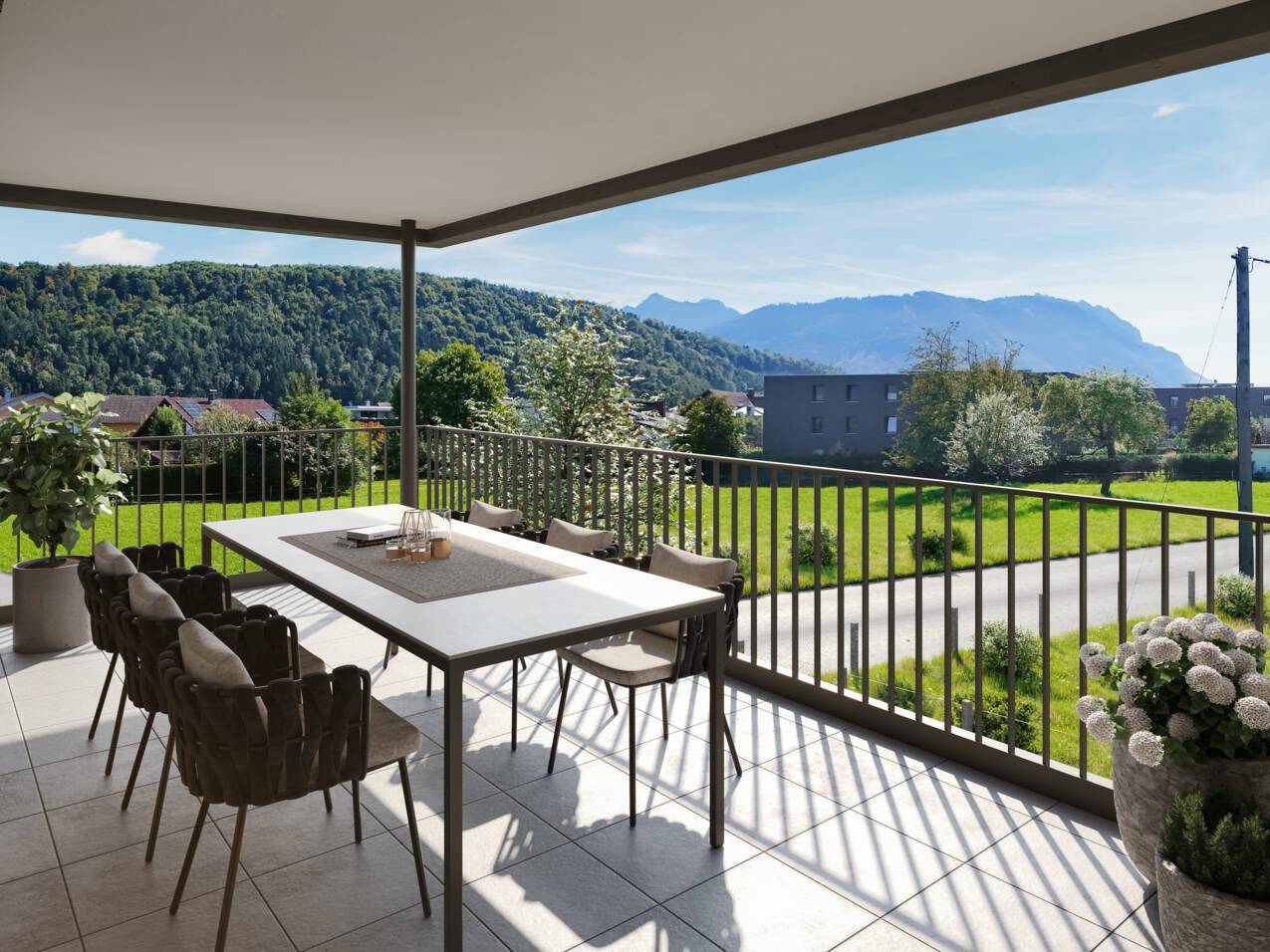 Geräumiger überdachter Balkon mit Esstisch und Stühlen, bietet einen weiten Blick auf die Berge.