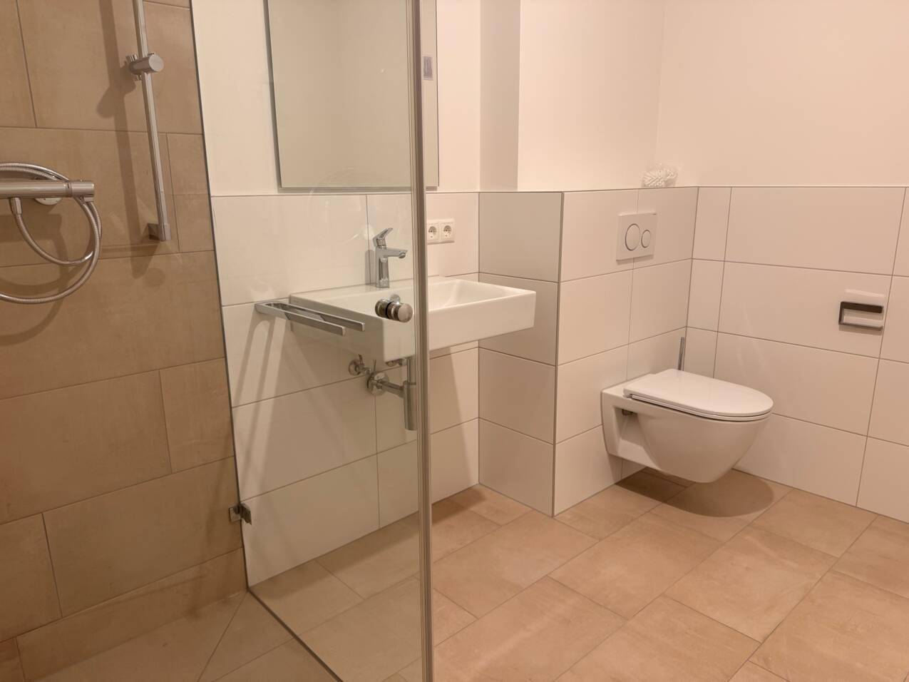 Modernes Badezimmer mit begehbarer Dusche, wandhängendem WC und weißen Fliesen.