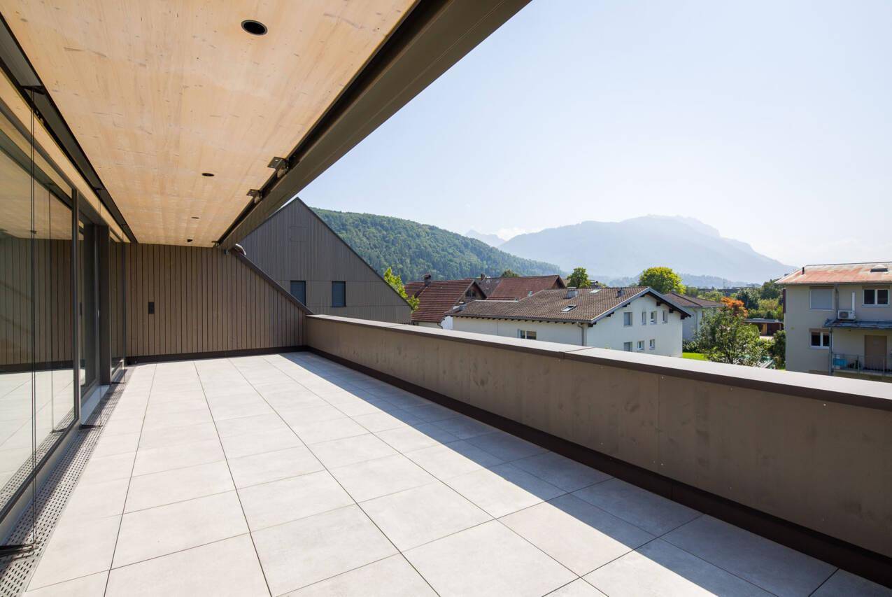 Geräumige Sonnenterrasse mit Fliesenboden und weitem Panoramablick auf die umliegende Berglandschaft.