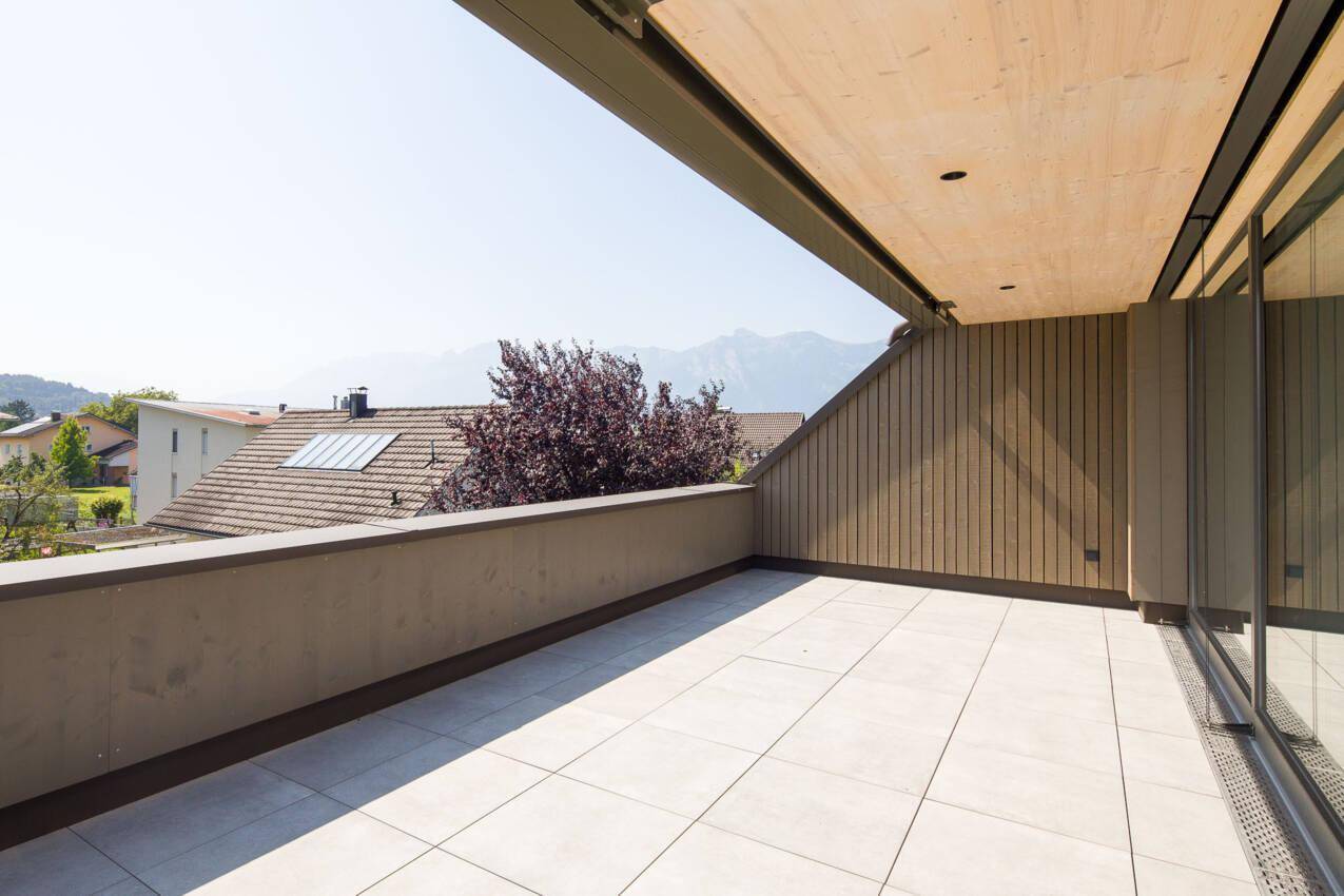 Sonniger Terrassenbereich mit moderner Holzverkleidung und beeindruckendem Bergblick in der Ferne.