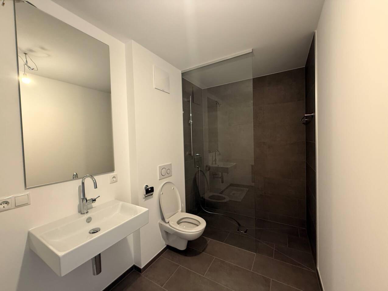 Modernes Badezimmer mit ebenerdiger Dusche, Wand-WC und eleganten Fliesen.