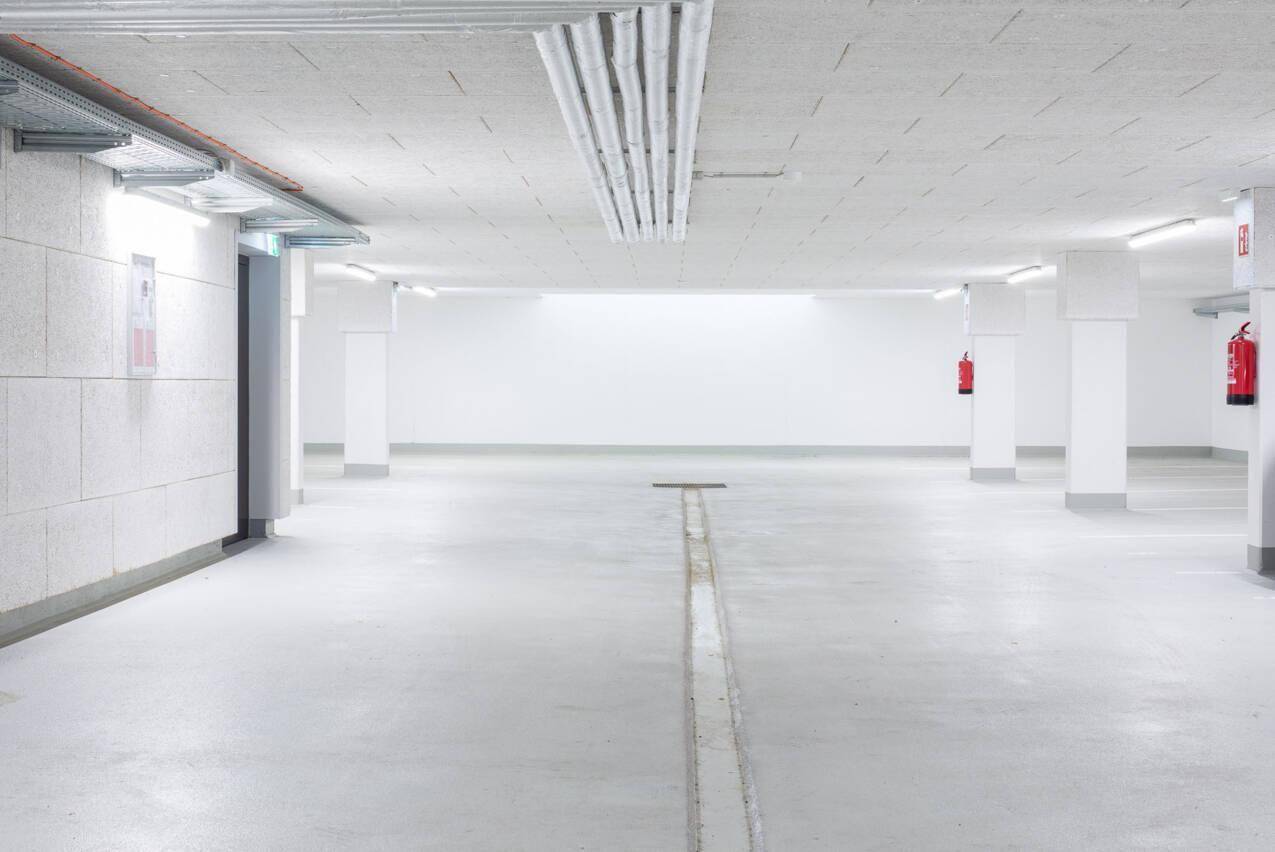 Geräumige Tiefgarage mit Betonboden und guter Beleuchtung, bietet Stellplätze.