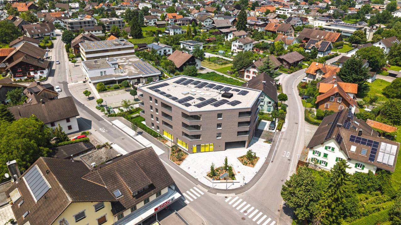 Luftaufnahme des modernen Wohngebäudes mit Photovoltaikanlage auf dem Dach in einer Wohnsiedlung.
