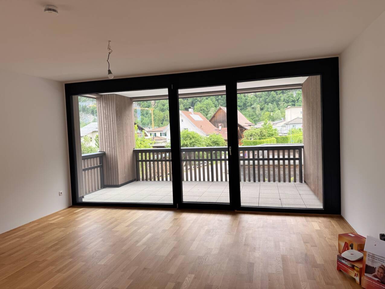 Geräumiges Wohnzimmer mit Holzboden und großem Balkon mit Bergblick.