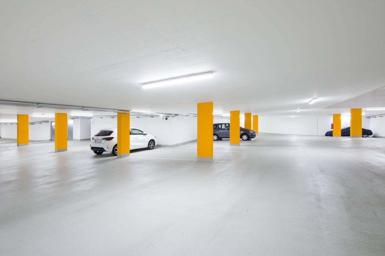 Geräumige Tiefgarage mit hellgrauem Boden und gelben Säulen für mehrere Fahrzeuge.