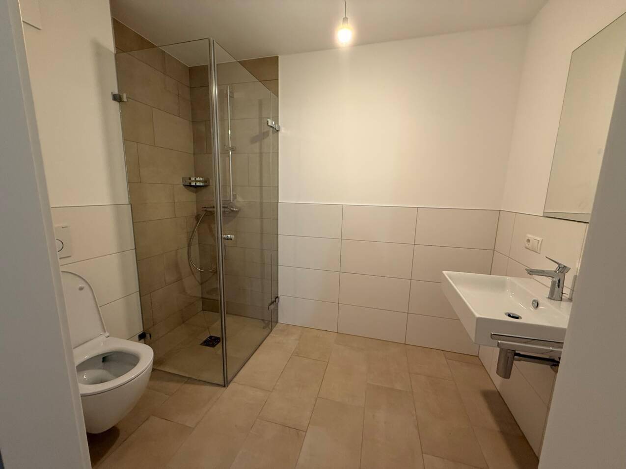 Modernes Badezimmer mit ebenerdiger Dusche, Wand-WC und hellem Fliesenboden.