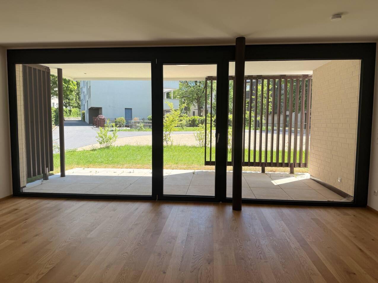 Helles Wohnzimmer mit großen Fensterfronten, Holzboden und direktem Zugang zur Terrasse und Garten.