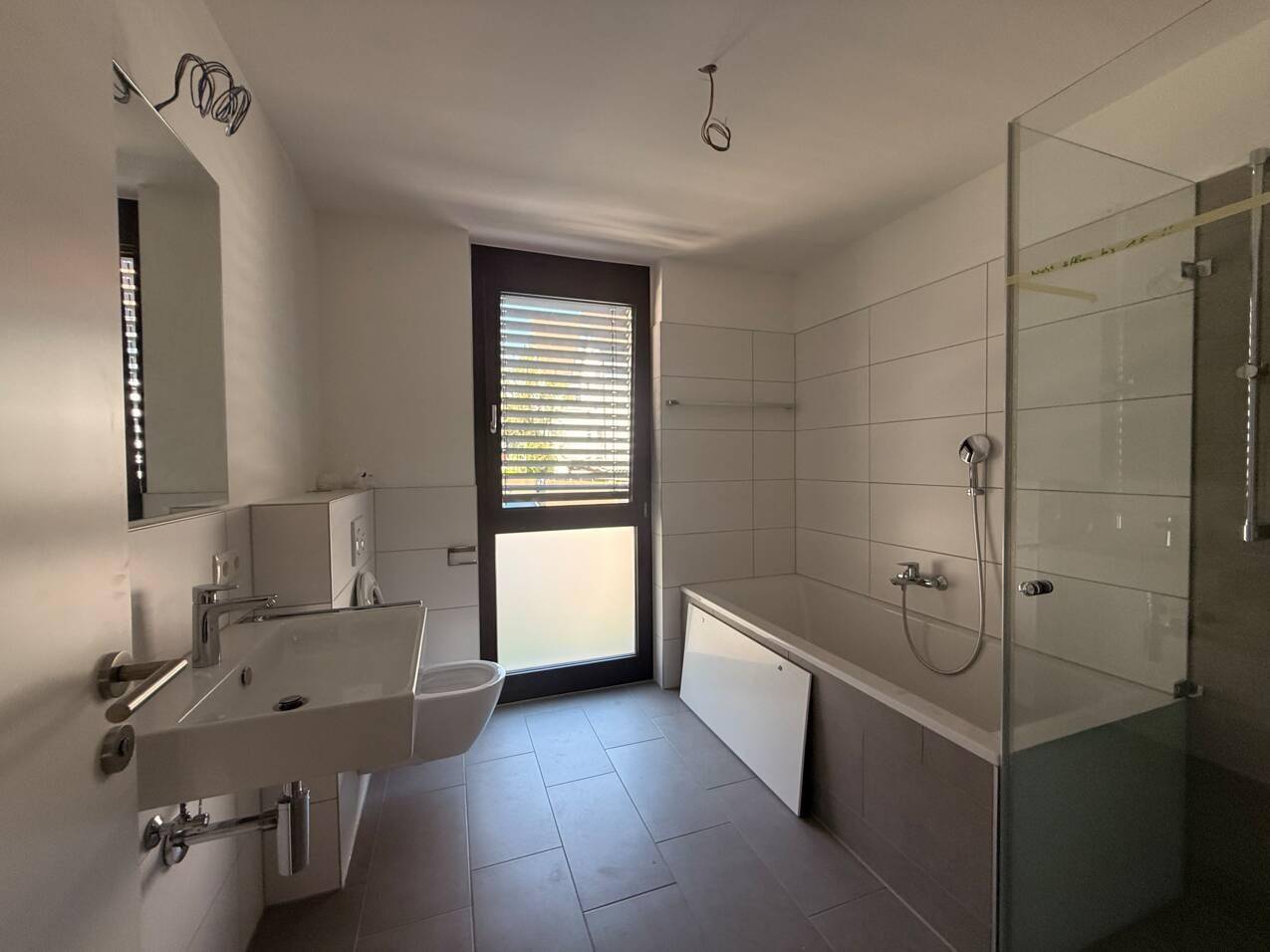 Modernes Badezimmer mit Badewanne, ebenerdiger Dusche und Fenster für natürliches Licht.
