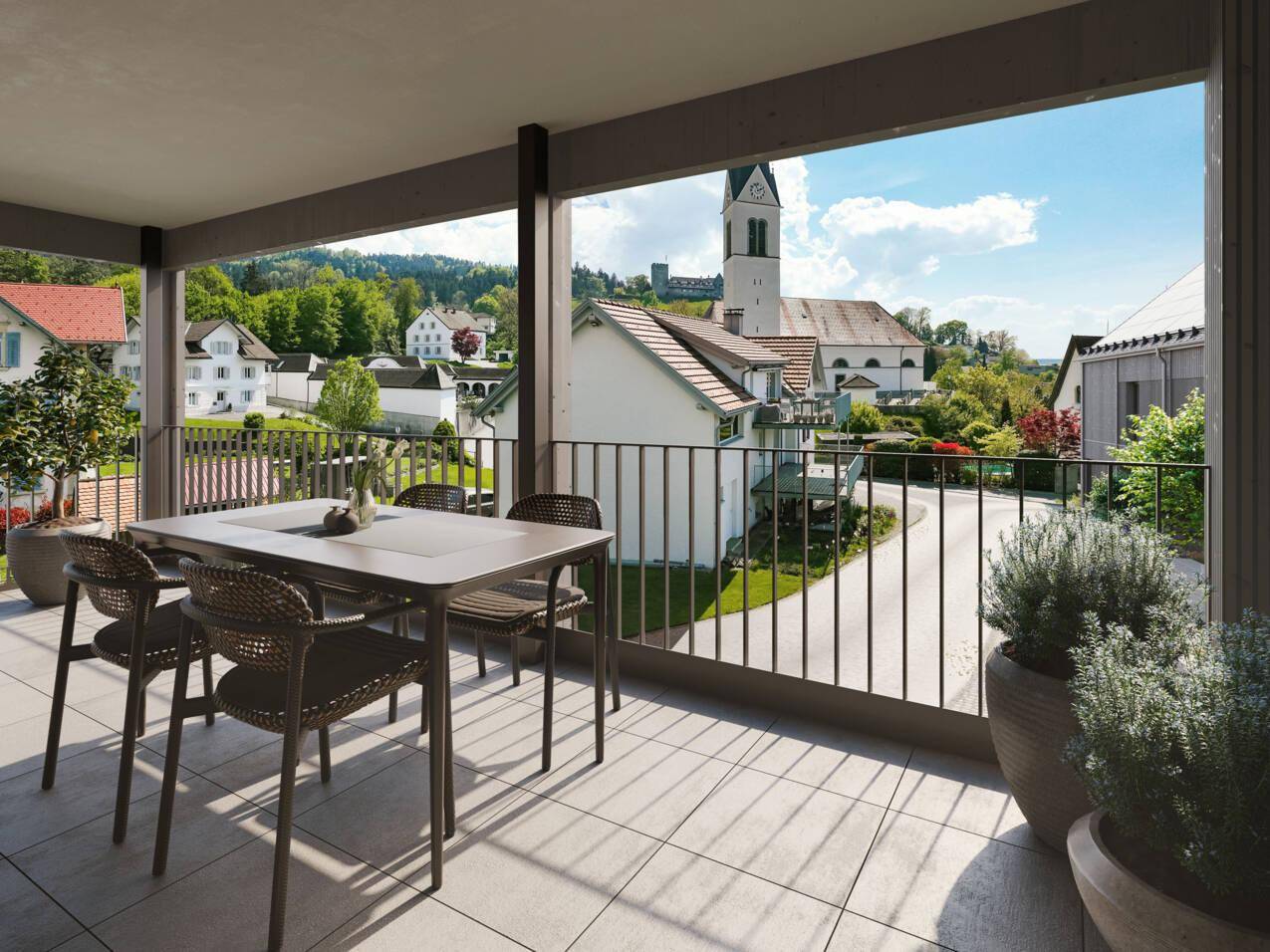 Geräumiger Balkon mit Essbereich und weitem Blick über die umliegende Ortschaft und Kirche.