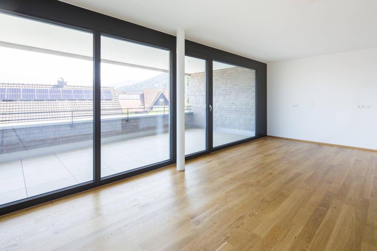 Geräumiger, heller Raum mit Eichenparkett und großen Schiebetüren zum Balkon.