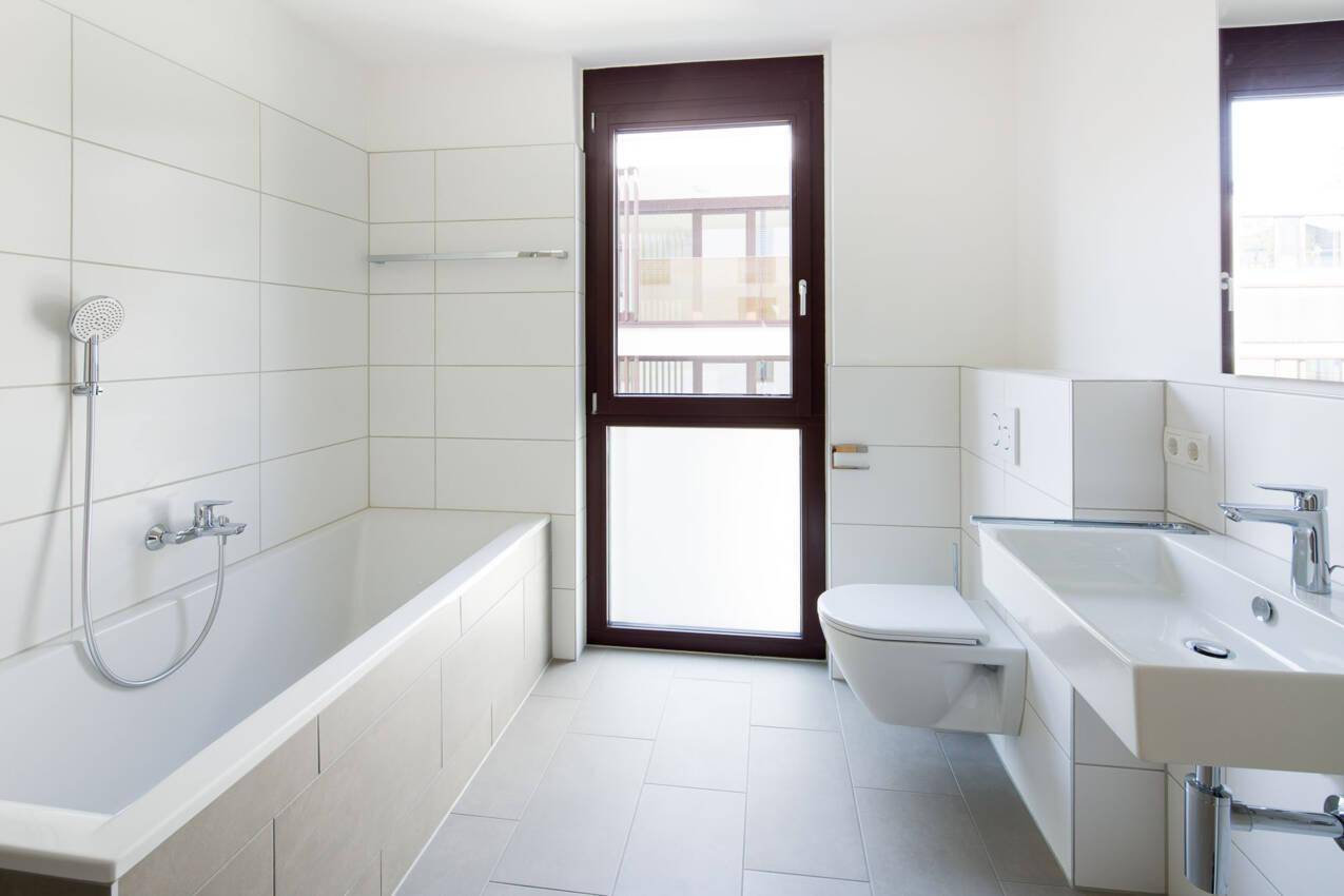Modernes Badezimmer mit Badewanne, wandhängendem WC, großem Waschbecken und Fenster.