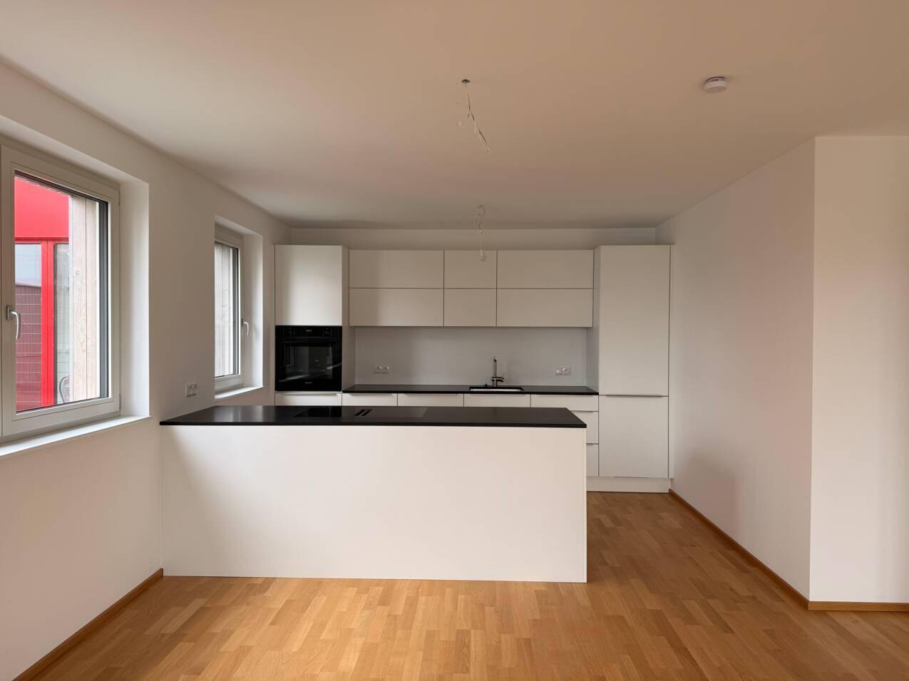 Helle, moderne Küche mit weißen Schränken, dunkler Arbeitsplatte und Holzboden.