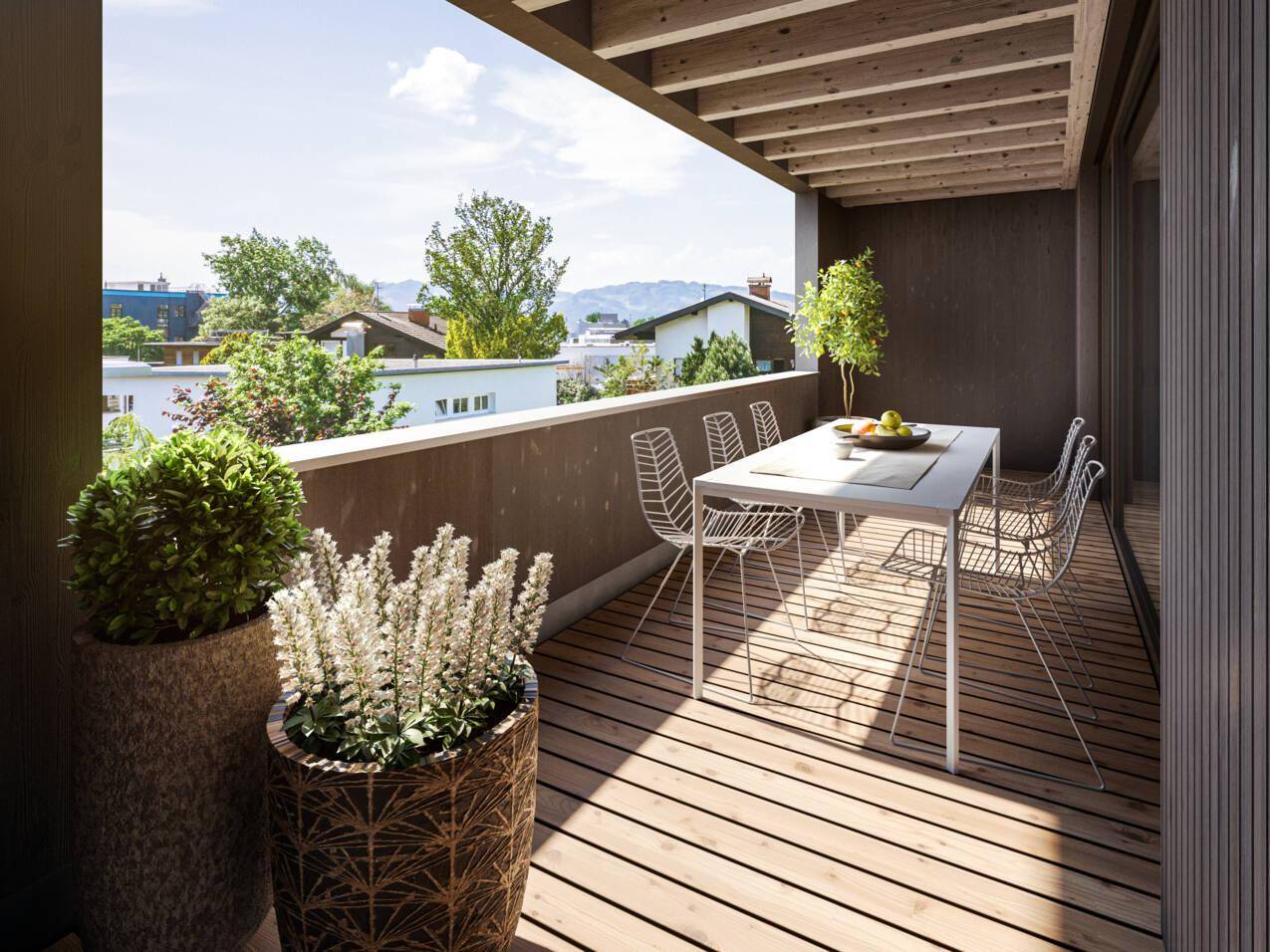Geräumiger Balkon mit Holzboden, modernen Gartenmöbeln und weitem Blick auf die Umgebung.