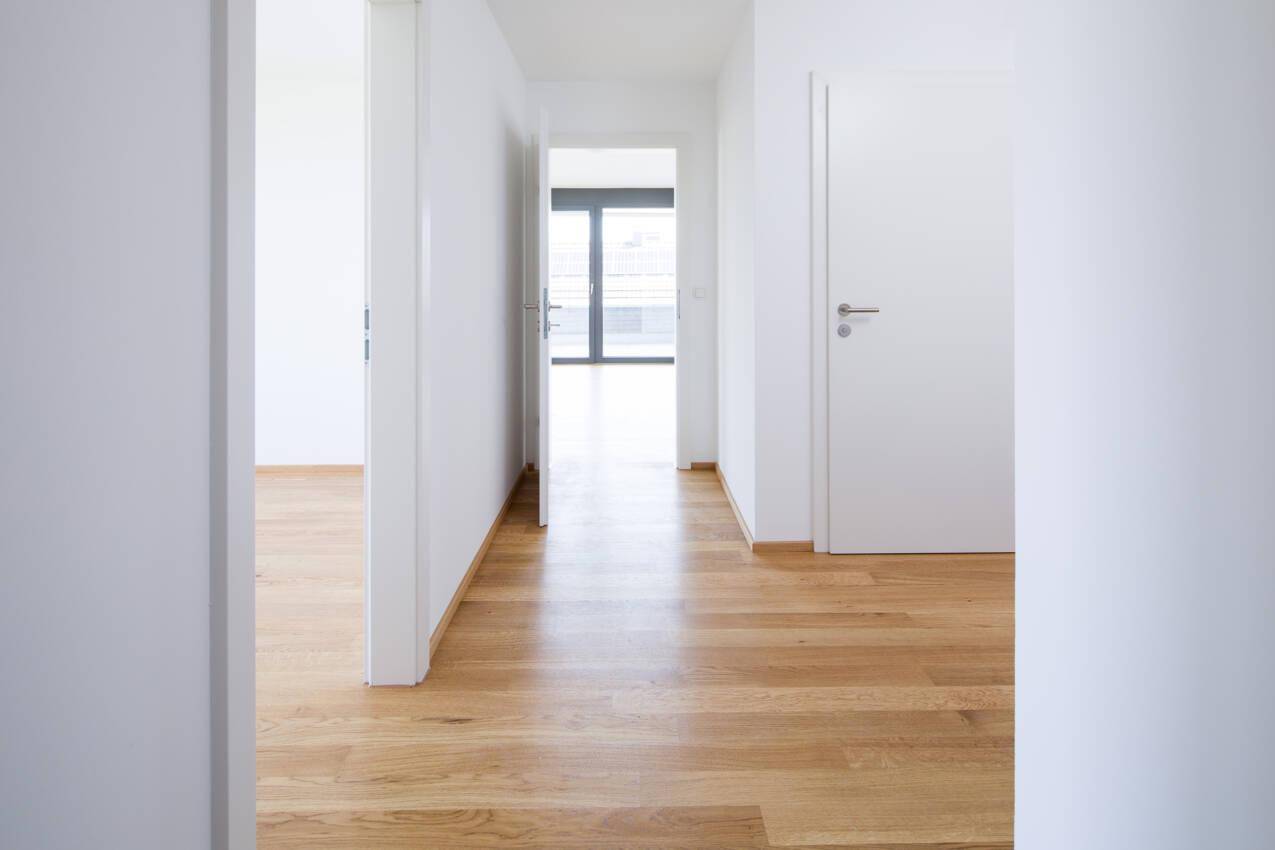Heller Flur mit Eichenparkettboden und weißen Wänden, der zu weiteren Räumen führt.