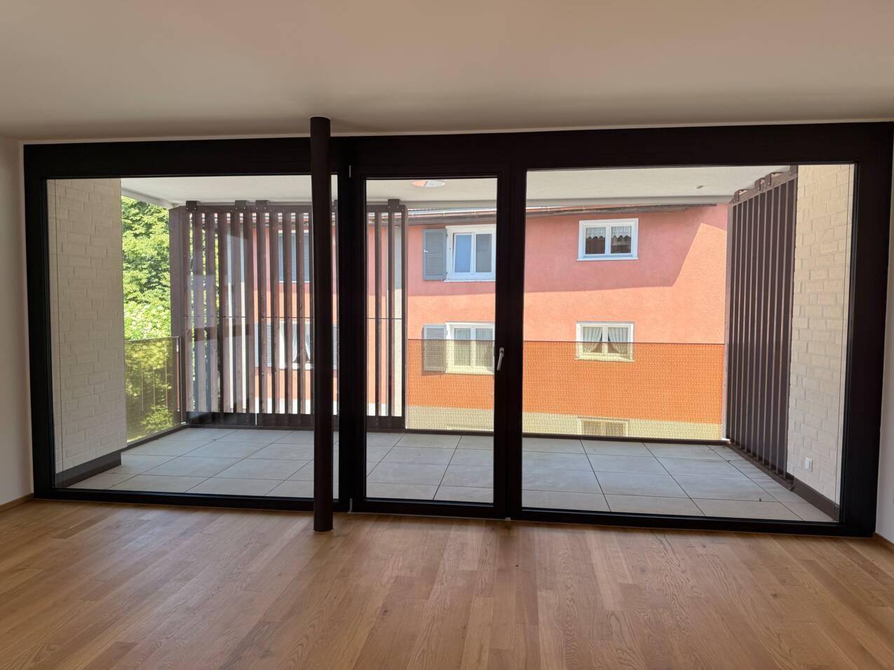 Heller Wohnbereich mit Parkettboden und Zugang zu einem geräumigen Balkon mit Blick auf die Umgebung.