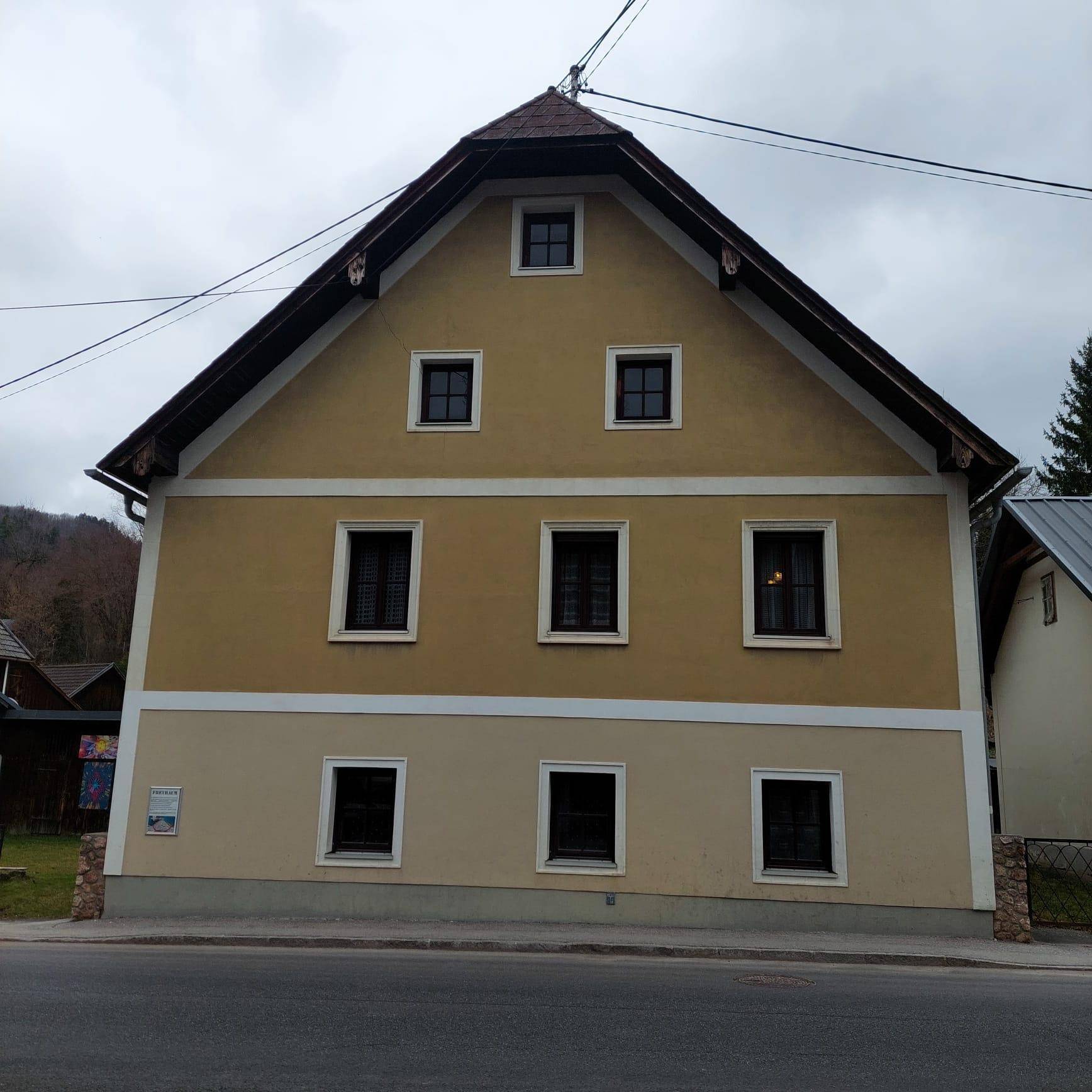 Vorderansicht des traditionellen Gebäudes mit mehreren Fenstern und Satteldach.
