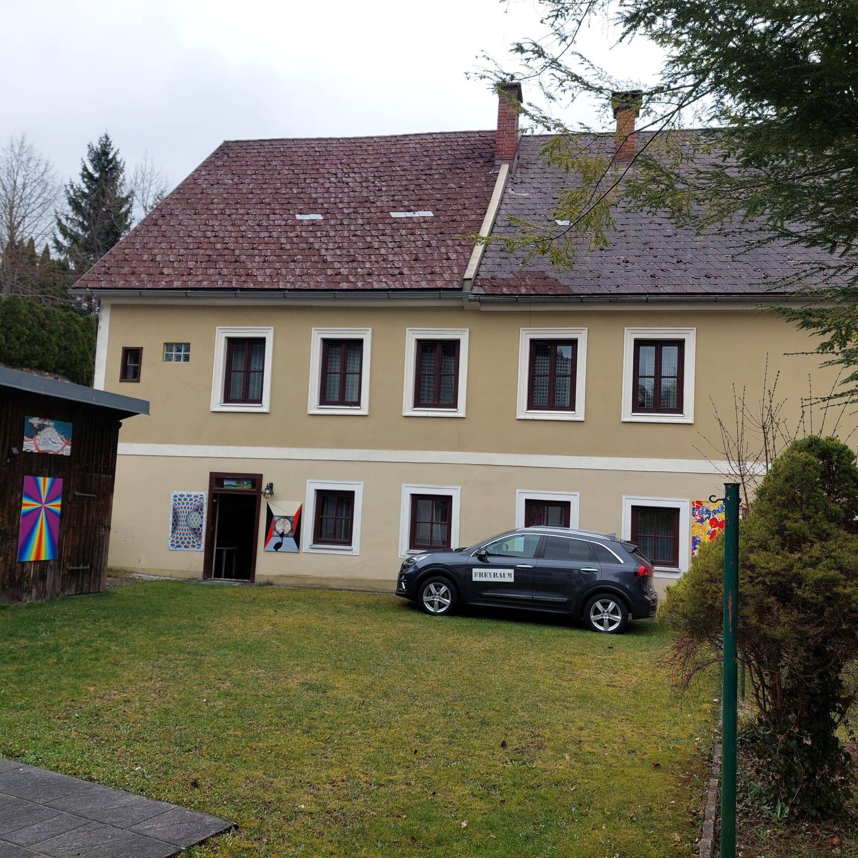 Seitenansicht des Gebäudes mit einem gepflegten Rasen und geparktem Auto.