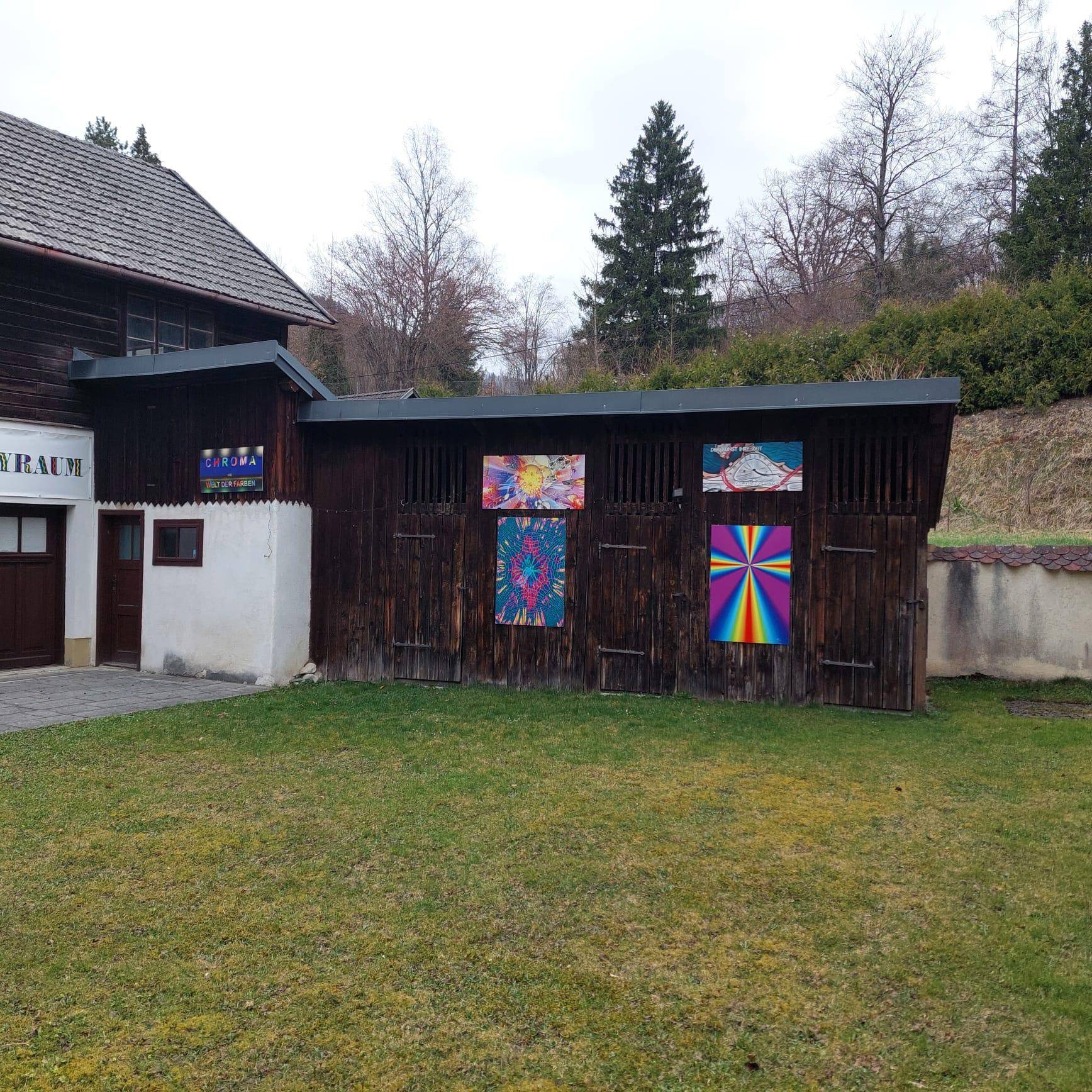 Gepflegter Rasen vor einem Nebengebäude mit Holzwänden und weiteren farbenfrohen Kunstwerken.
