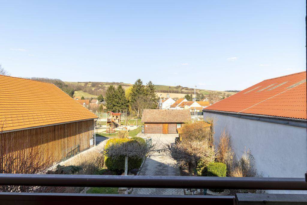 Weitblick vom Balkon über eine ländliche Umgebung mit Häusern, Feldern und einem Spielplatz.