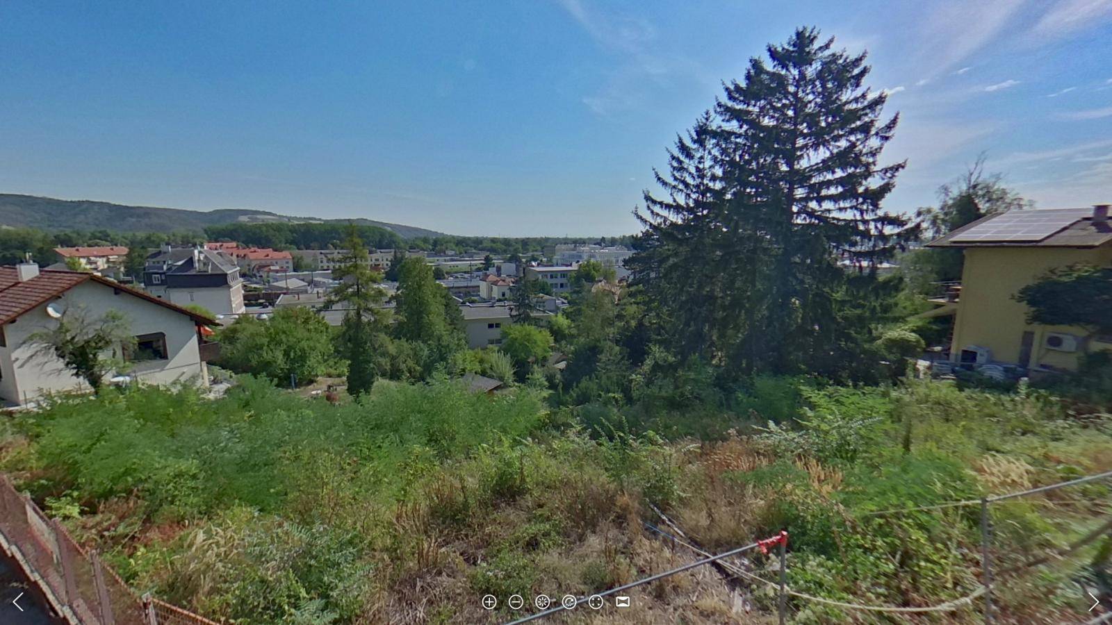 Panoramablick über eine Stadtlandschaft mit vielen Bäumen und Häusern unter strahlend blauem Himmel.